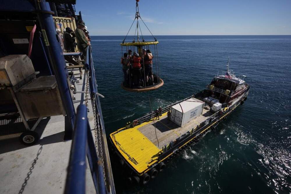 Expedition 501 members in a Billy Pugh basket are lowered from the Liftboat Robert platform to the Gaspee. (Carolyn Kaster/AP)