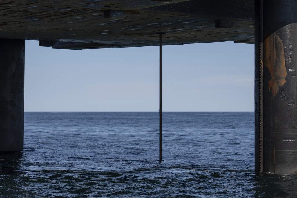The wireline drilling core barrel is visible from the underside of the Liftboat Robert platform, from a crew transport vessel, in the North Atlantic, Saturday, July 19, 2025. (Carolyn Kaster/AP)