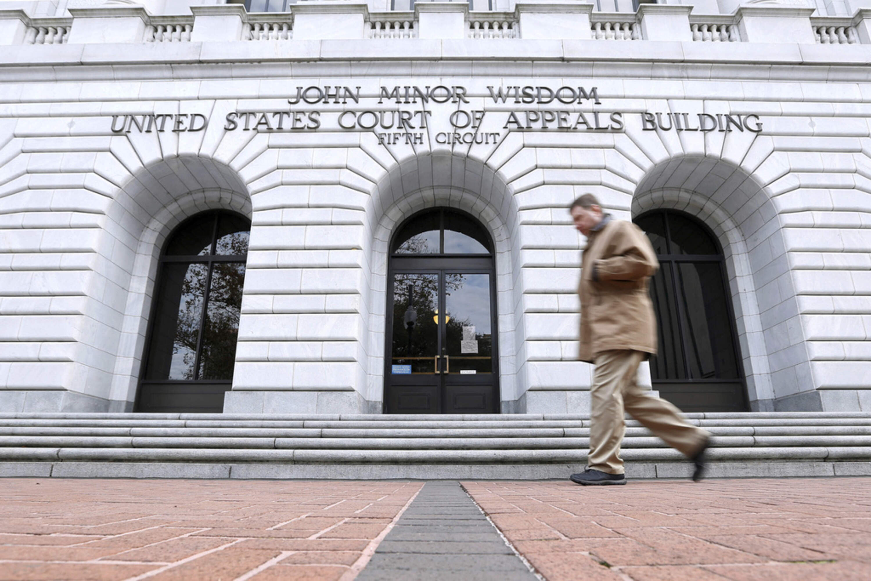 A man walks in front of the 5th U.S. Circuit Court of Appeals, Jan. 7, 2015, in New Orleans. (AP Photo/Jonathan Bachman, File)