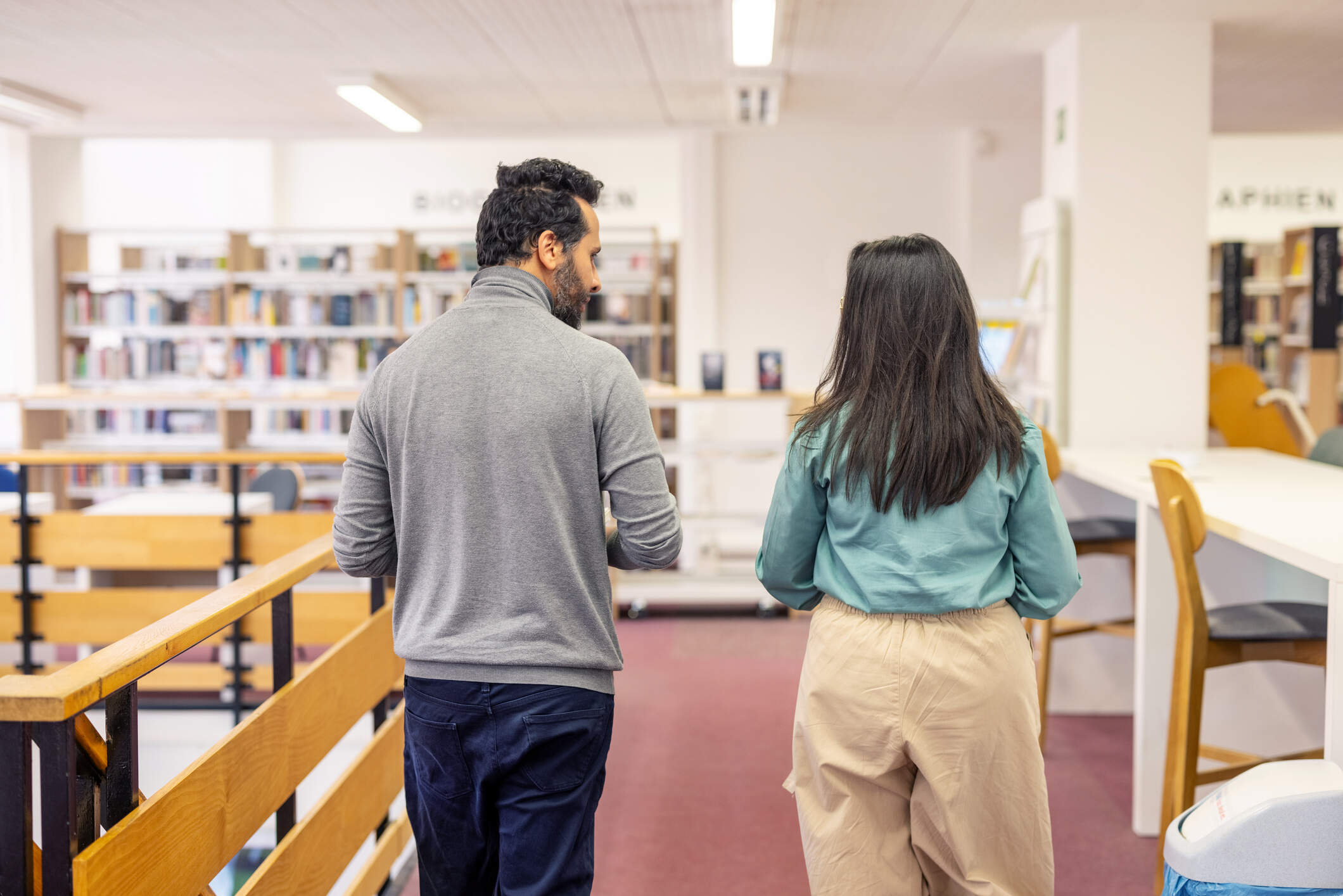 A man and a woman engaged in conversation while walking through a public library. (Getty Images)