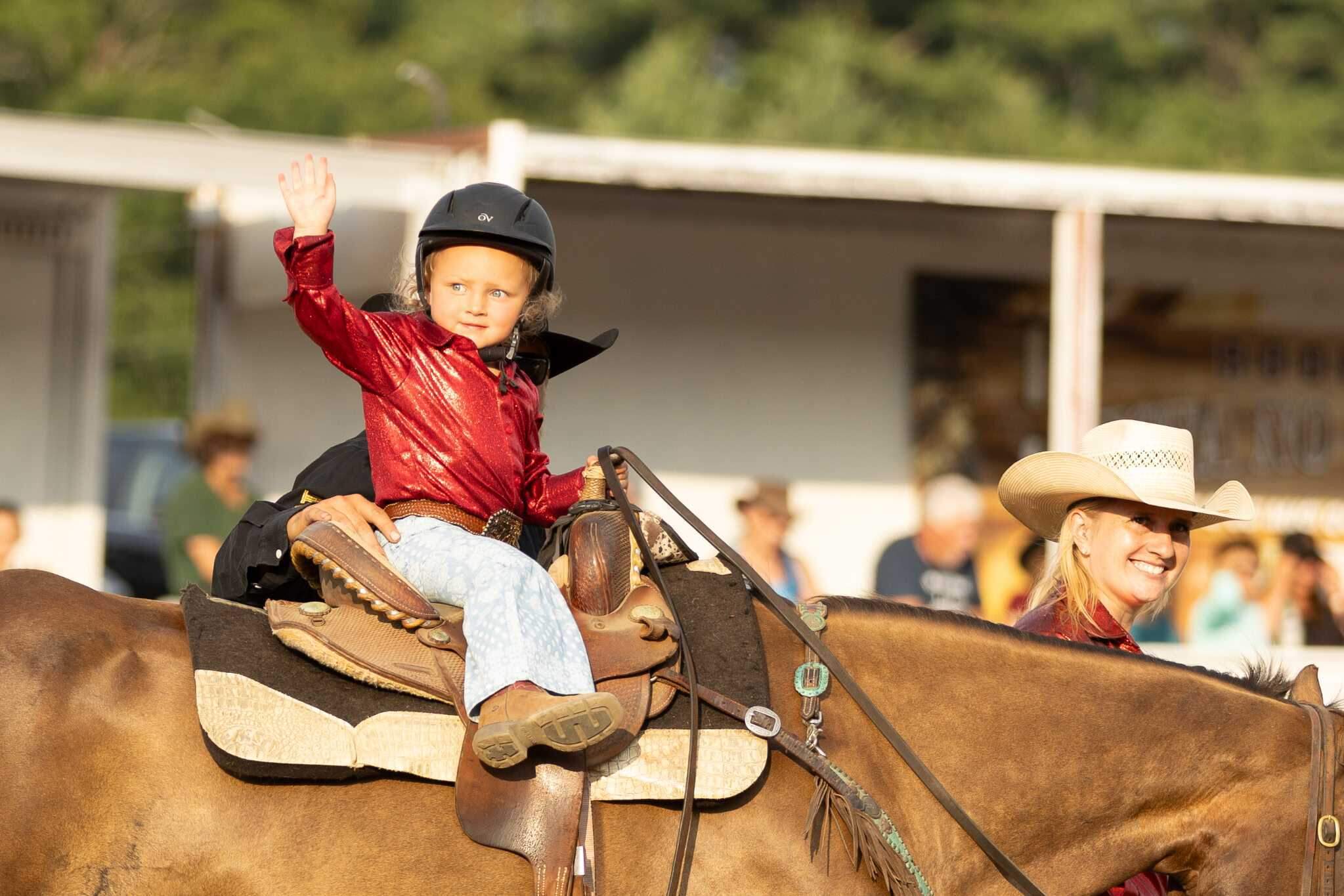 A child waves while riding horseback at the New England Rodeo. (Jenn Carmichael/Flex It Photography)