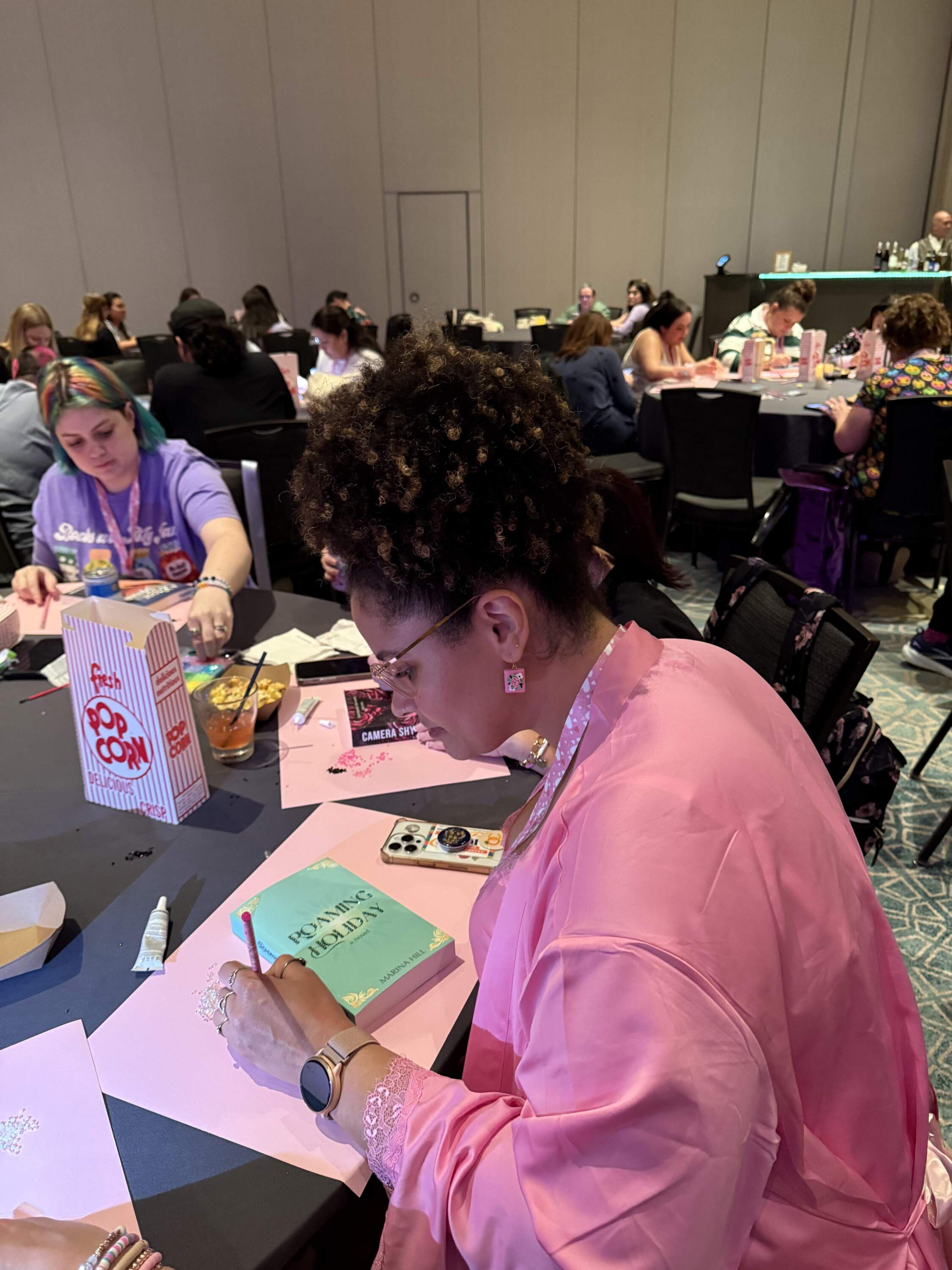 Robyn-Cherry Siegler at the pajama party event during the Romantically Yours Book Convention, bejeweling a copy of Marina Hill’s “Roaming Holiday” (Hafsa Quraishi/Here & Now)