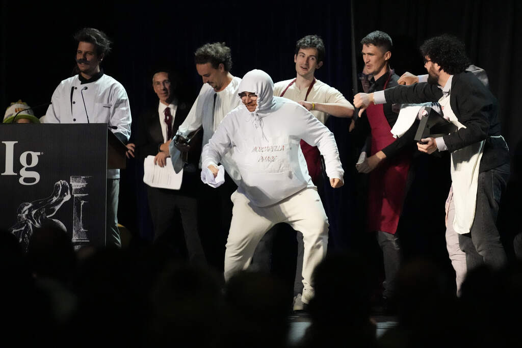 The Ig Nobel Prize for nutrition is accepted by Daniele Dendi, Gabriel H. Segniagbeto, Roger Meek, and Luca Luiselli, for studying the extent to which a certain kind of lizard chooses to eat certain kinds of pizza. (Robert F. Bukaty/AP)