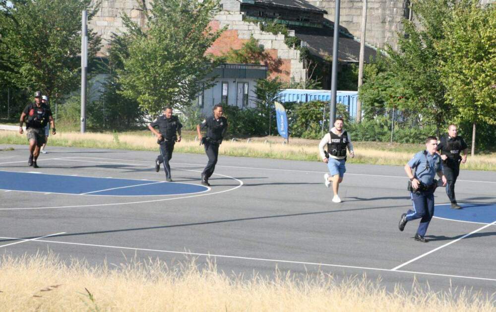 Boston Police officers and SWAT team members ran from the residence hall at UMass Boston to a report of shots fired in the campus center about a half-mile away in the middle of the chaotic incident. (Seth Daniel/Dorchester Reporter)
