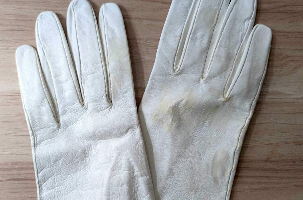 A pair of white leather gloves with yellow water stains. (Hanna Ali/WBUR)