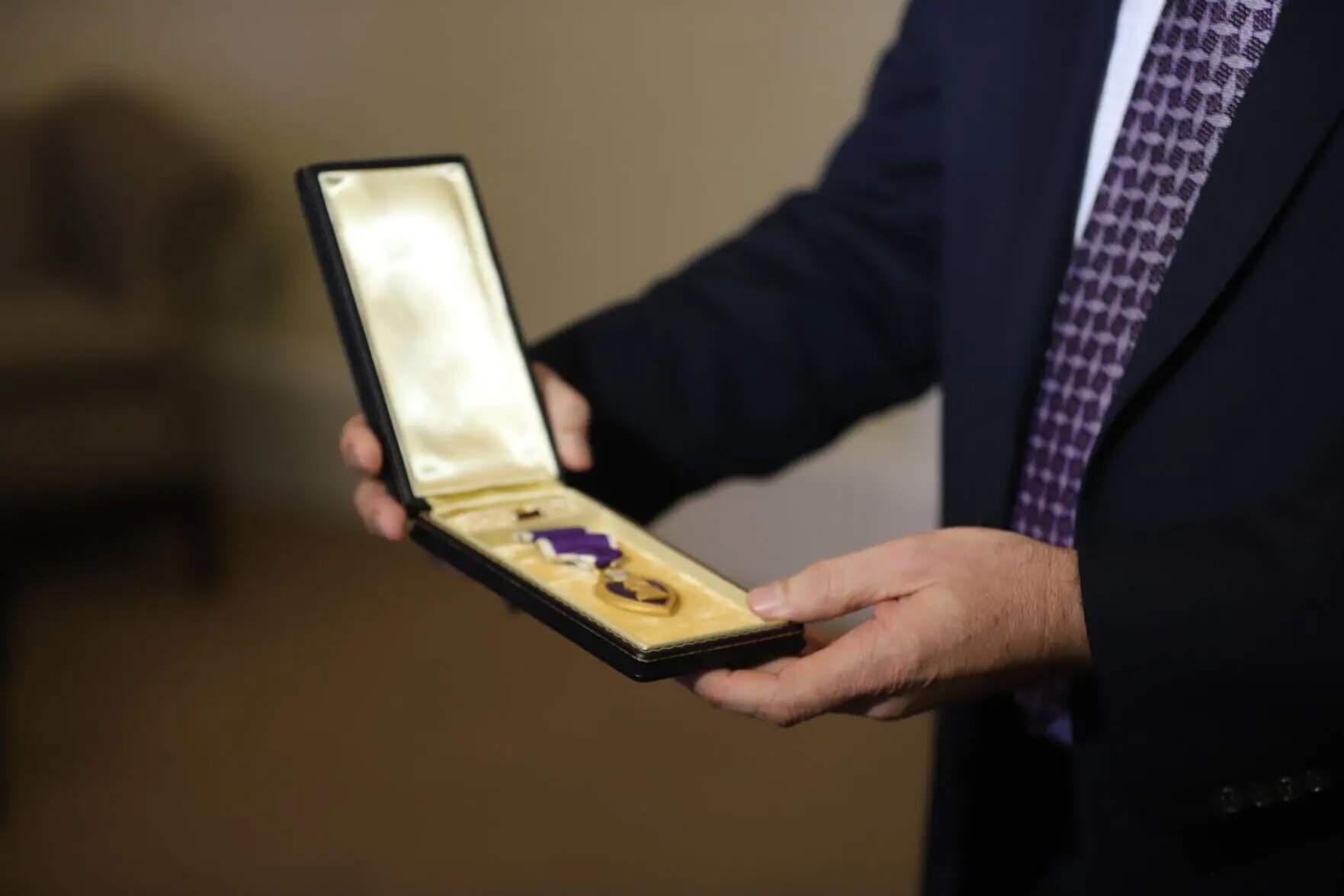 Thomas Brigham, the grandson of Purple Heart recipient Sgt. Thomas Flynn, holds the medal that his grandfather earned in World War I. (Colin A. Young/SHNS)
