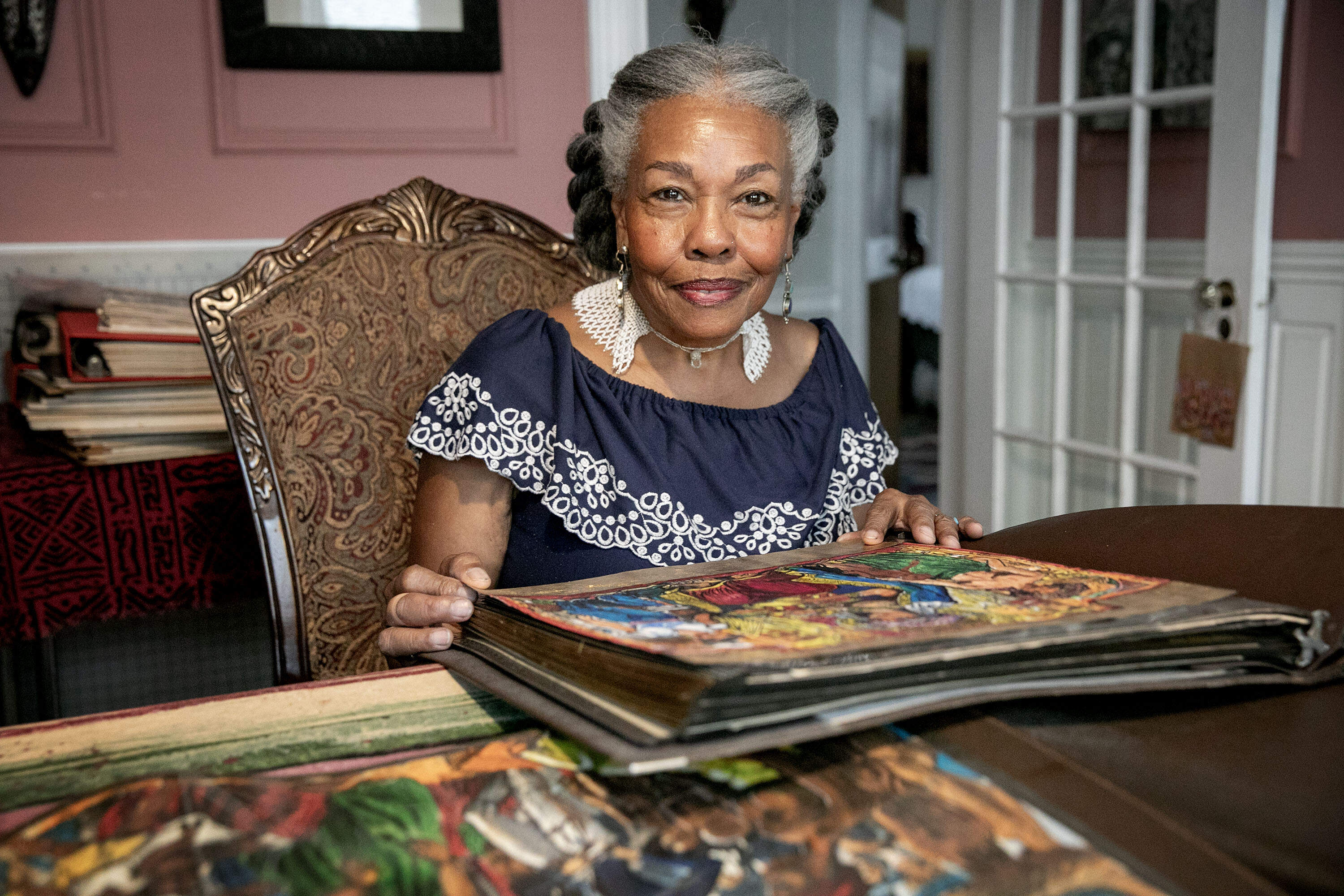 Artist Susan Thompson looks through a folder of Allan Rohan Crite's work, at her home in Boston. (Robin Lubbock/WBUR)