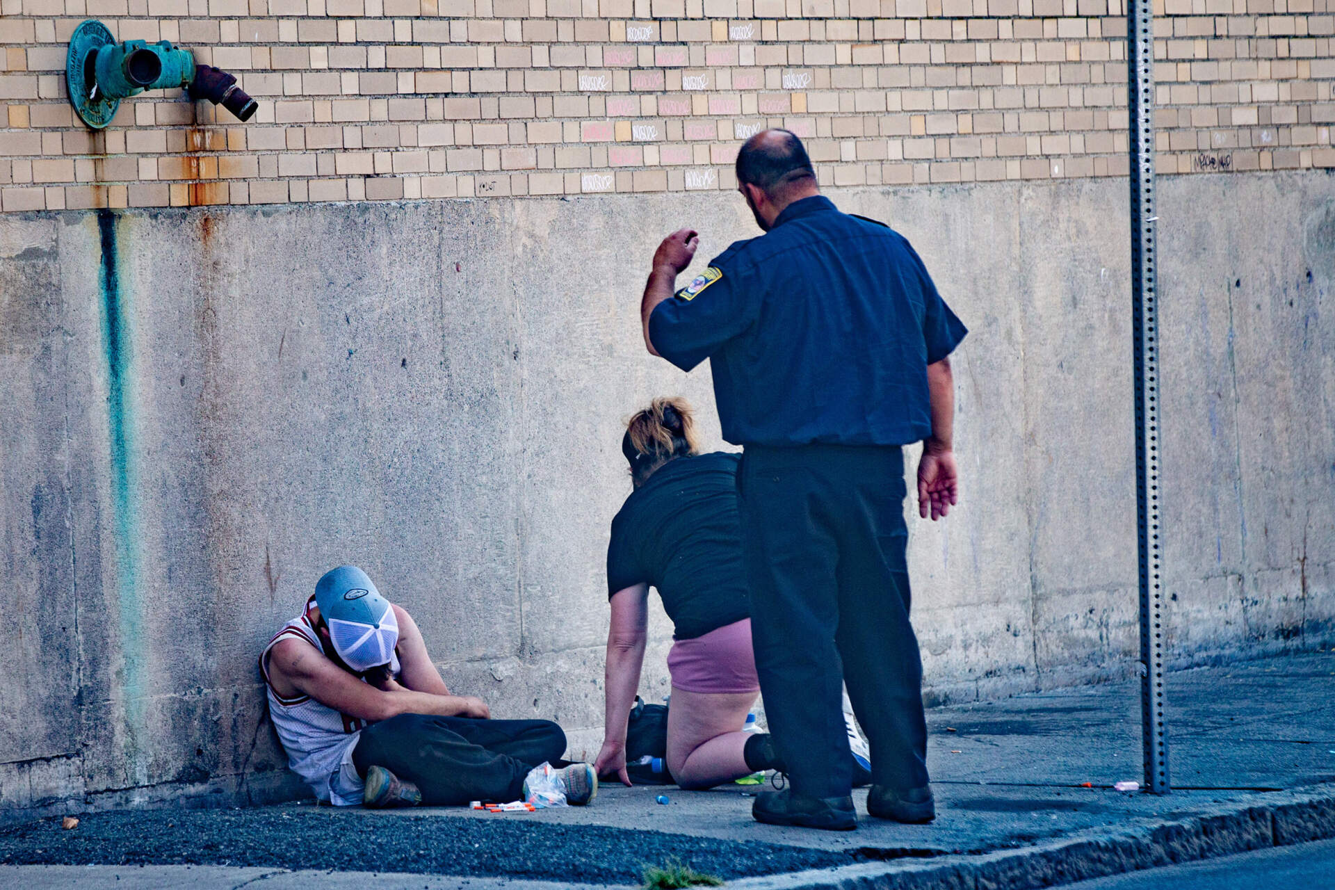 Newmarket Business Improvement District Public Safety Officer Mark Murphy helps a woman get up as he attempts to move her and another person away from a business on Atkinson Street this past summer. 