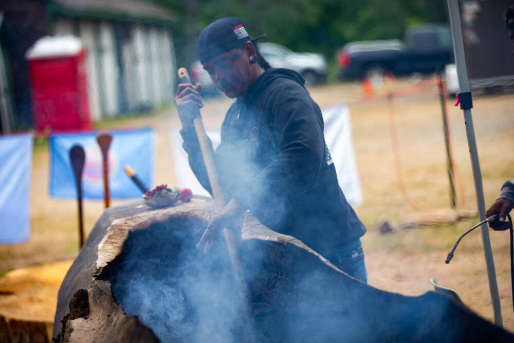 Andre StrongBearHeart tends the fire during a mishoon burning camp at the Norcross Wildlife Foundation. (Jesse Costa/WBUR)