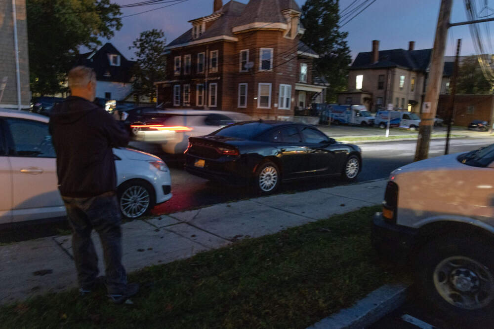 A volunteer with LUCE observes a vehicle on Pearl Street in Framingham. (Robin Lubbock/WBUR)