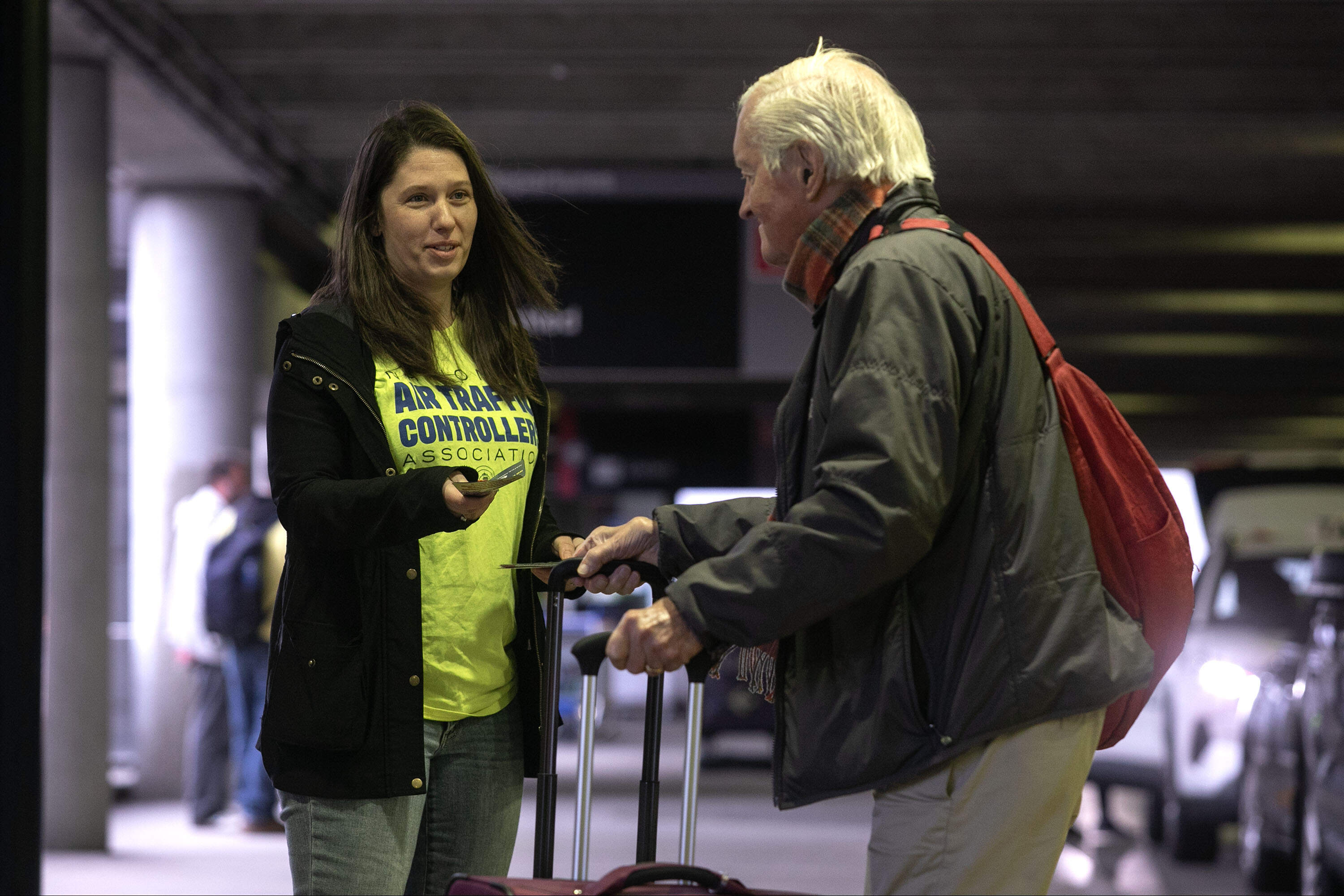Air Traffic Controller Alyssa Nena hands a leaflet from the National Air Traffic Controllers Association (NATCA) to a traveler at Logan Airport's Terminal B. (Robin Lubbock/WBUR)