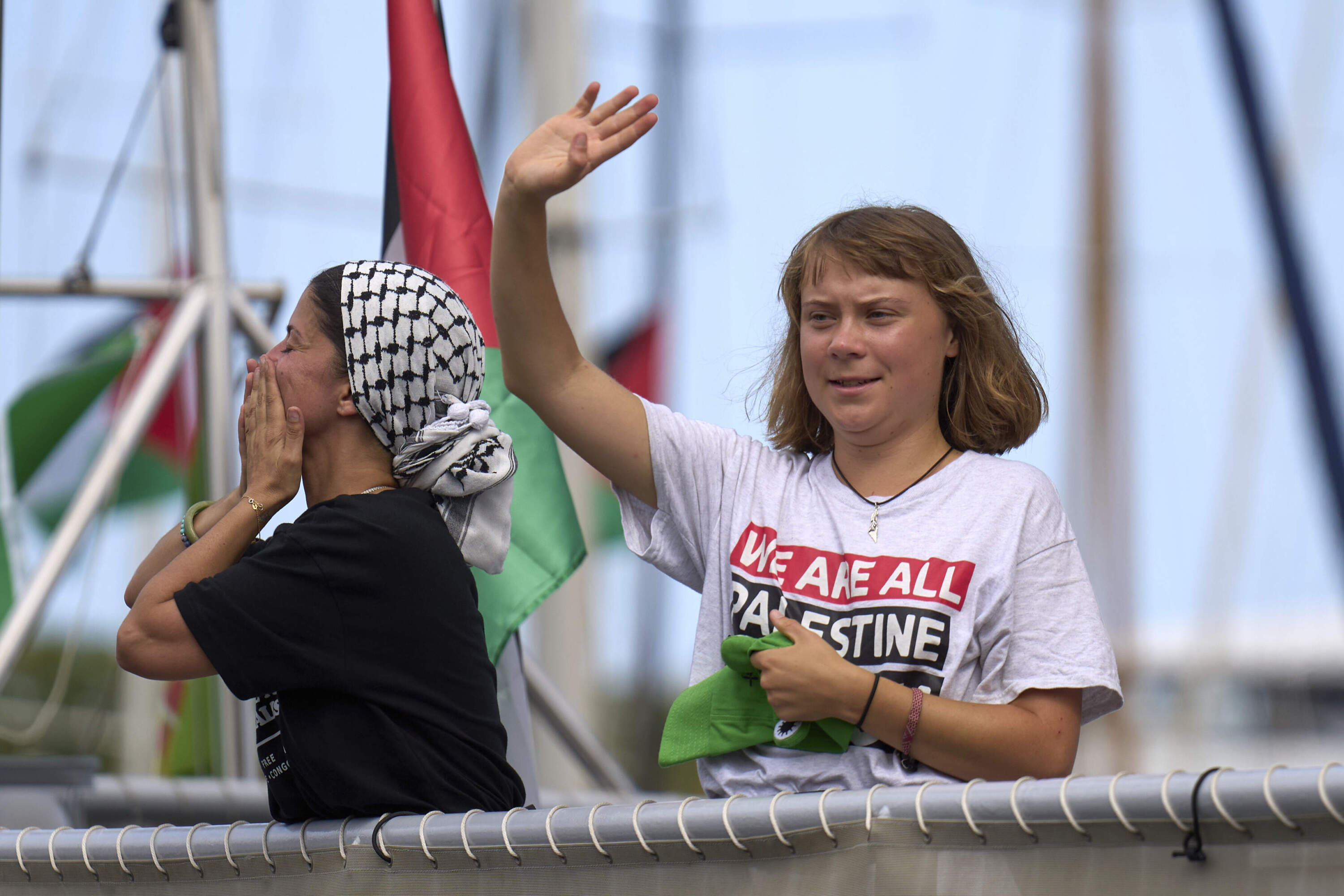 Swedish climate activist Greta Thunberg waves from a boat taking part in a civilian flotilla bound for Gaza, aiming to break the Israeli blockade and deliver humanitarian aid, in Barcelona, Spain, Sunday, Aug. 31, 2025. (Emilio Morenatti/AP)