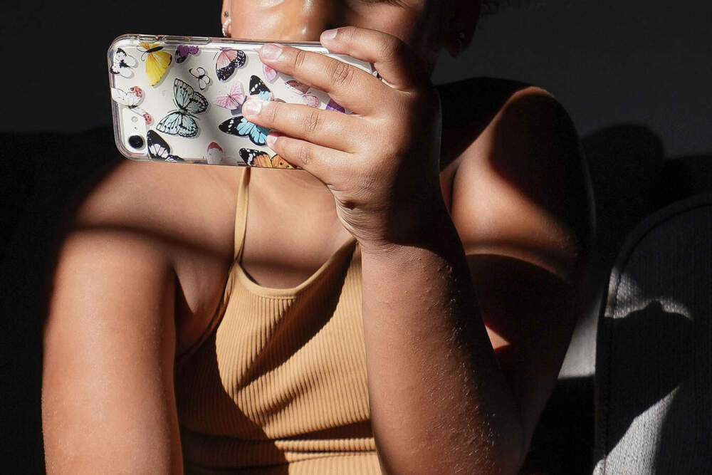A girl uses her smartphone at home in Arizona on Friday, June 16, 2023. (Darryl Webb/AP)