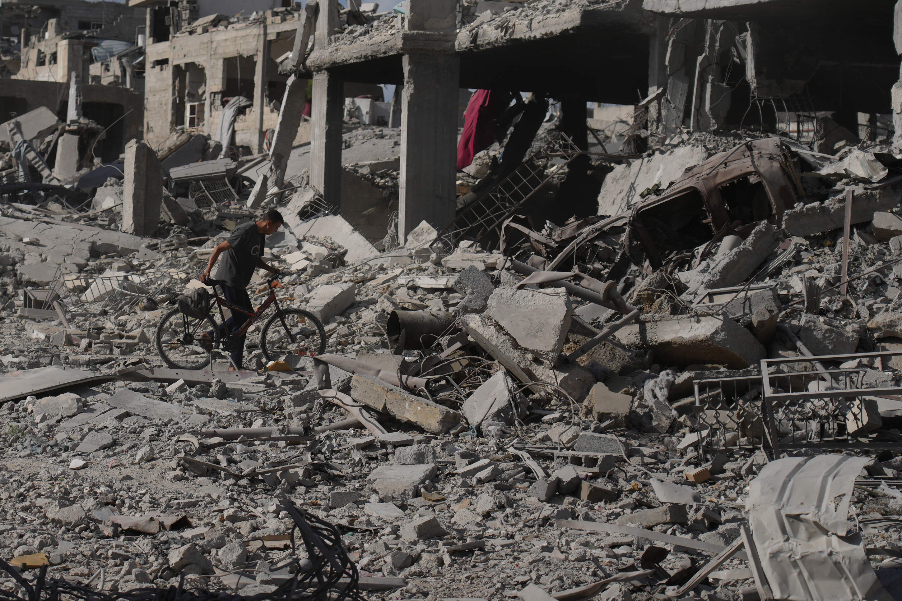 A man pushes his bicycle through rubble in Gaza City, Sunday, Oct. 12, 2025, after Israel and Hamas agreed to a pause in their war and the release of the remaining hostages. (Jehad Alshrafi/AP)