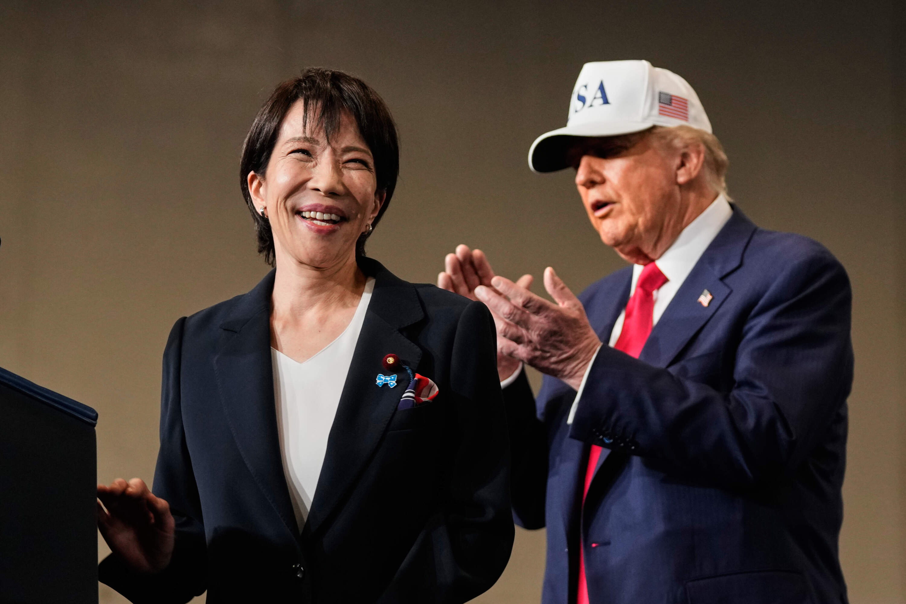Japanese Prime Minister Sanae Takaichi, with President Donald Trump, reacts as she was speaking to members of the military aboard the USS George Washington, an aircraft carrier docked at an American naval base, in Yokosuka, Tuesday, Oct. 28, 2025. (Mark Schiefelbein/AP)