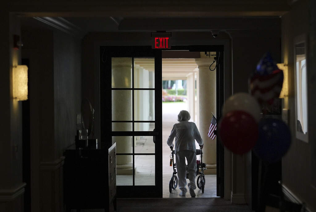 A woman uses a walker as she exits an assisted living building in Boca Raton, Fla. (AP Photo/Rebecca Blackwell)
