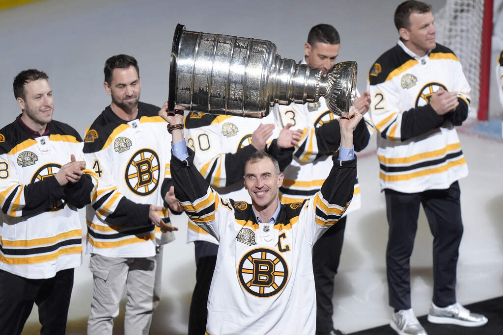 Former Boston Bruins defenseman Zdeno Chara, center, holds the Stanley Cup trophy above his head as he introduced with other former Bruins players before an NHL hockey game between the Toronto Maple Leafs and the Bruins, Thursday, March 7, 2024. (Steven Senne/AP)