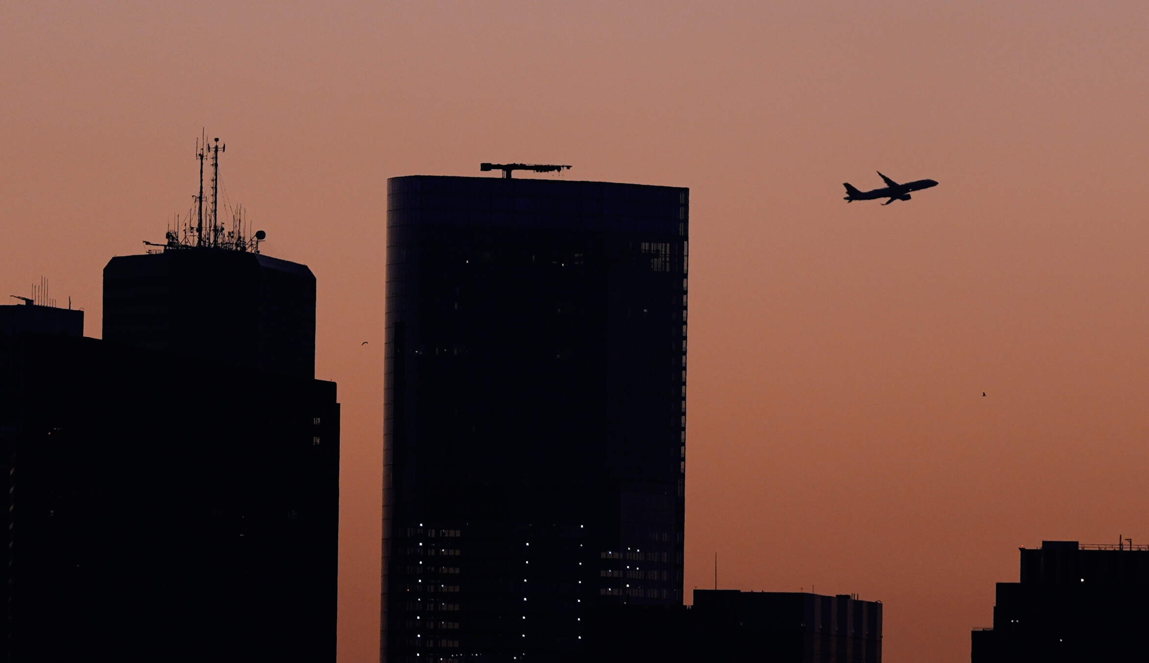 An airplane climbs from Logan Airport over downtown Boston at dawn this past Monday.