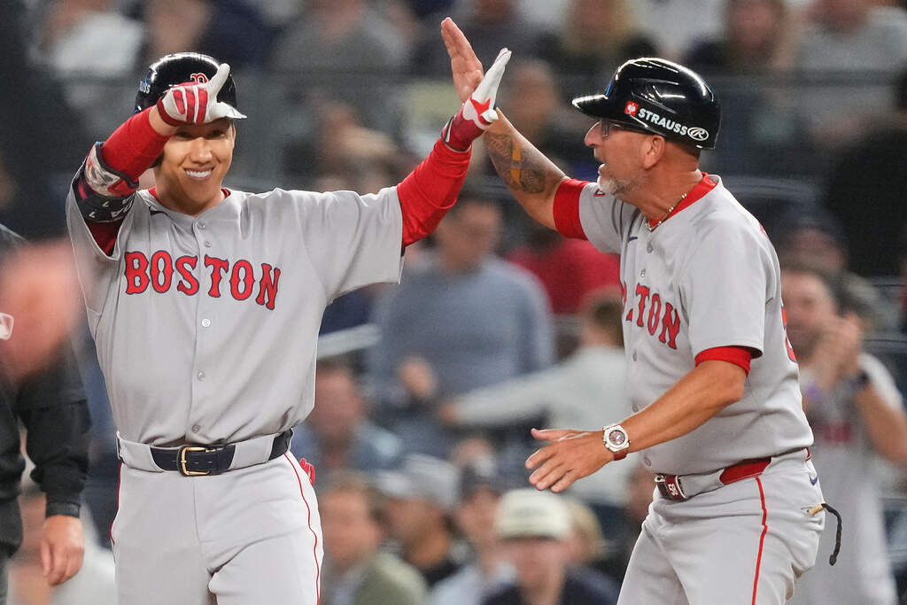 Boston Red Sox outfielder Masataka Yoshida, left, celebrates with first base coach José David Flores after driving in two runs against the New York Yankees during the seventh inning of Game 1 of an American League wild-card baseball playoff series, Tuesday, Sept. 30, 2025, in New York. (Yuki Iwamura/AP)