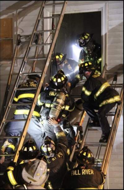 Crews rescue a Gabriel House resident from a second floor window the night of the fire on July 13. This image was included in the after action report (Photo by Kenneth Leger, courtesy the Fall River Fire Department)