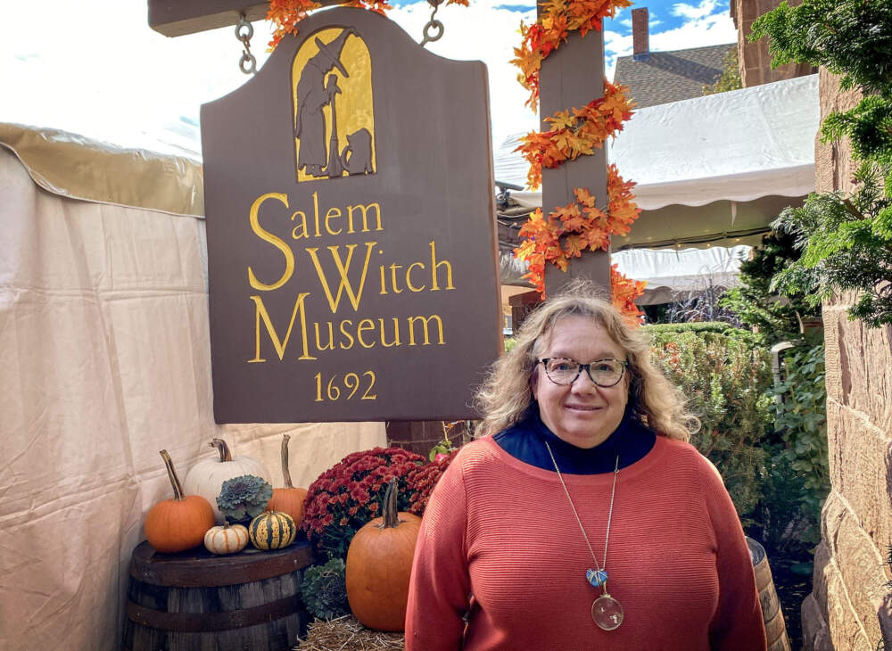 Tina Jordan, executive director of the Salem Witch Museum, stands by the museum's sign. (Andrea Shea/WBUR)