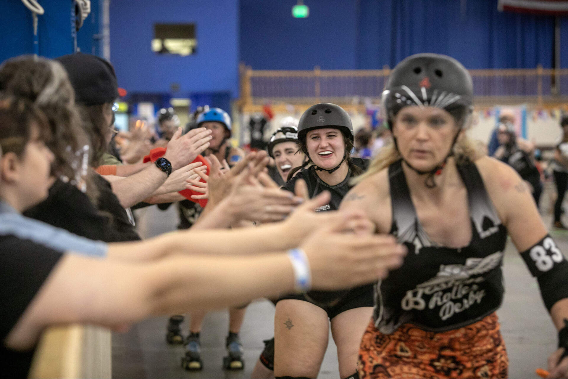 Boston Roller Derby players slap hands with their fans at a roller derby game in Wilmington, Mass. (Robin Lubbock/WBUR)