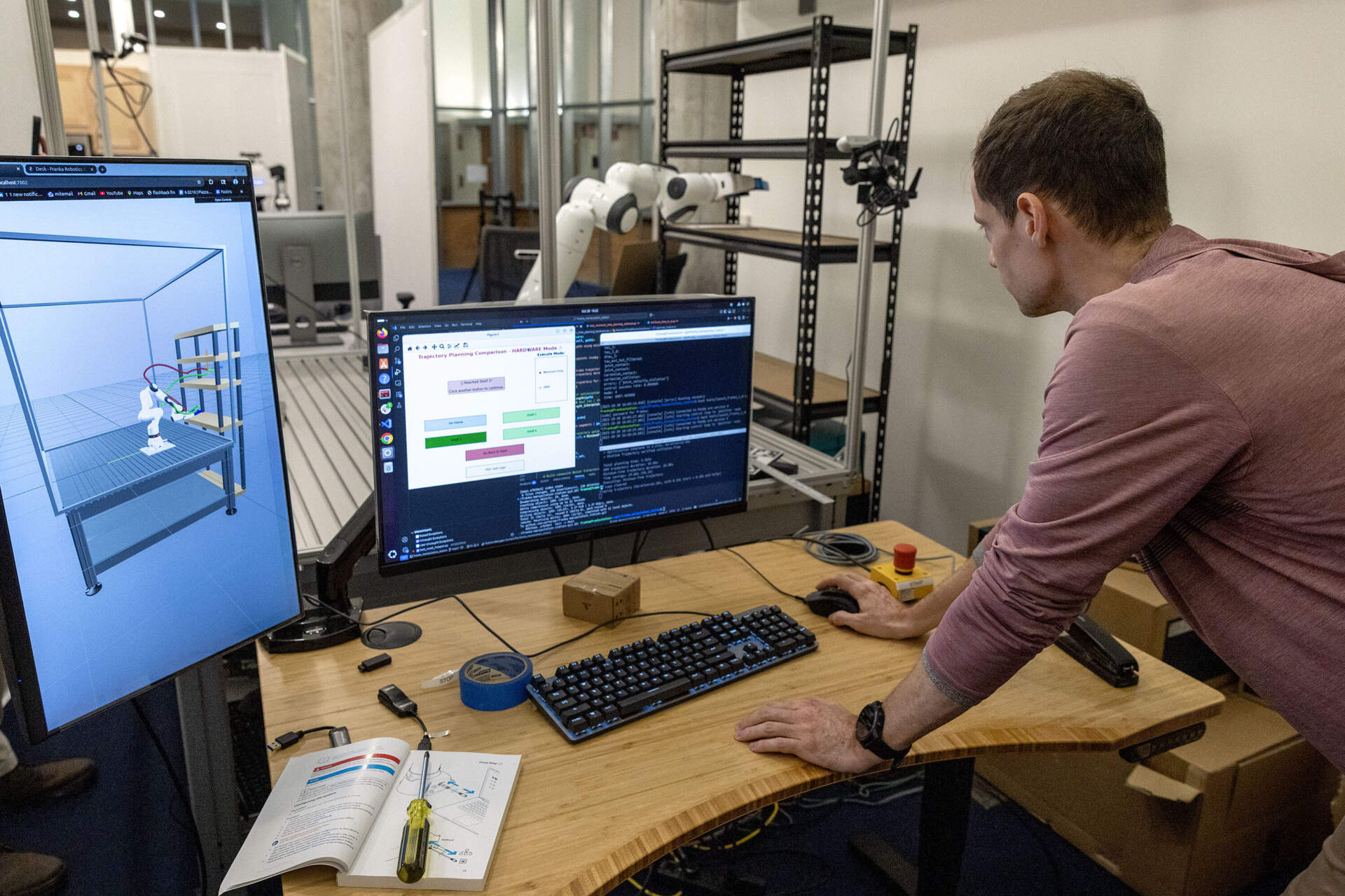 MIT doctoral candidate Peter Werner works on programming a robotic arm to stock shelves. (Robin Lubbock/WBUR)