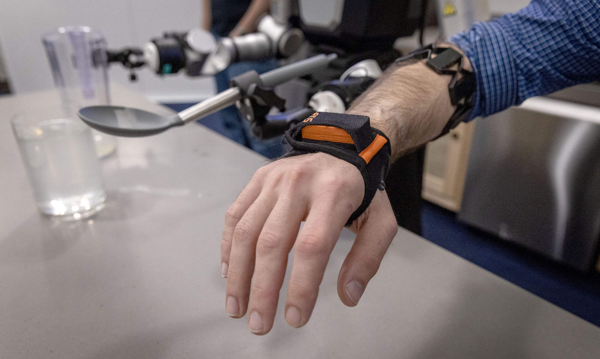 Researcher Joseph DelPreto shows how sensors are placed on a human arm to gather data to to train the robots. (Robin Lubbock/WBUR)