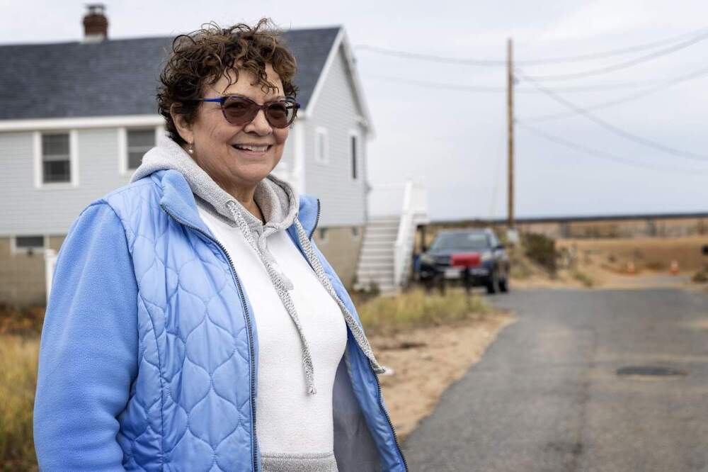 Lee McLaughlin in front of her former beachfront home on Plum Island. McLaughlin accepted a FEMA buyout of the house, which will be demolished. (Robin Lubbock/WBUR)
