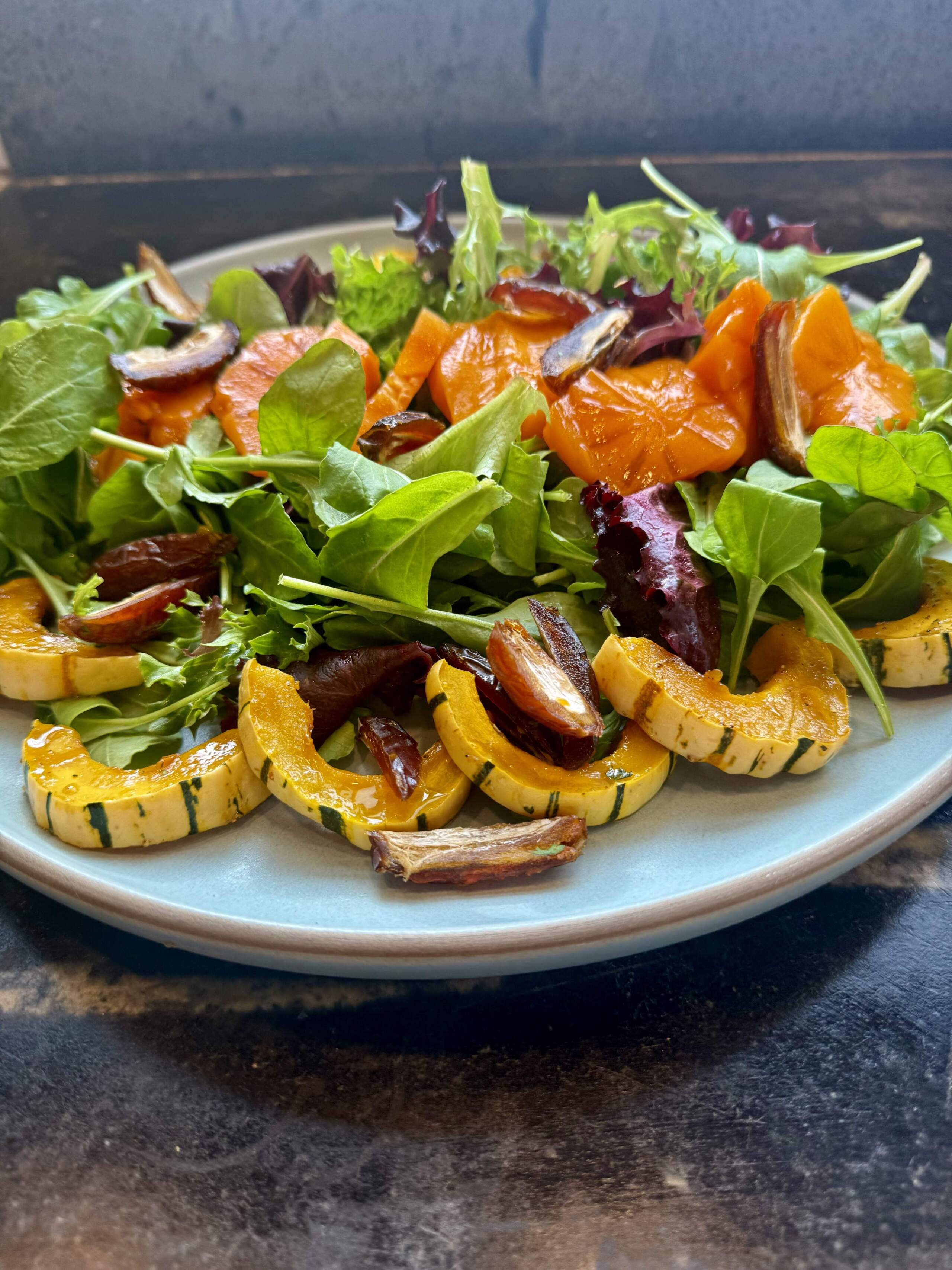 Arugula and salad greens with roasted maple squash, dates, and persimmons with a mustard-maple syrup vinaigrette. (Kathy Gunst/Here & Now)
