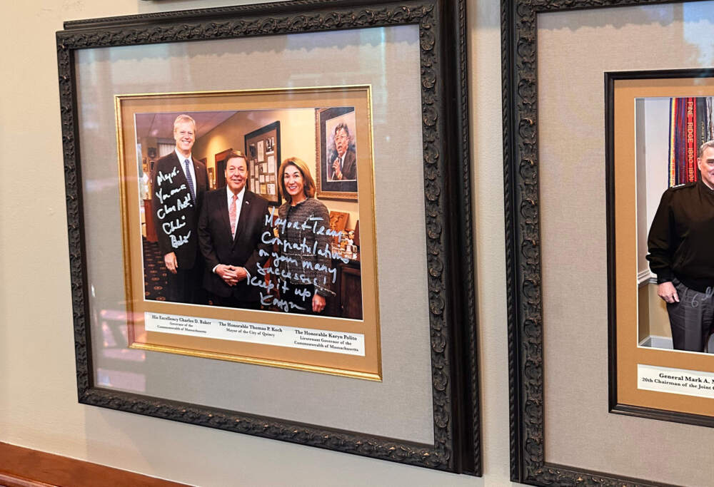 Mayor Tom Koch displays a signed photo in his office of him with former Gov. Charlie Baker and Lt. Gov. Karyn Polito. (Simón Rios/WBUR)