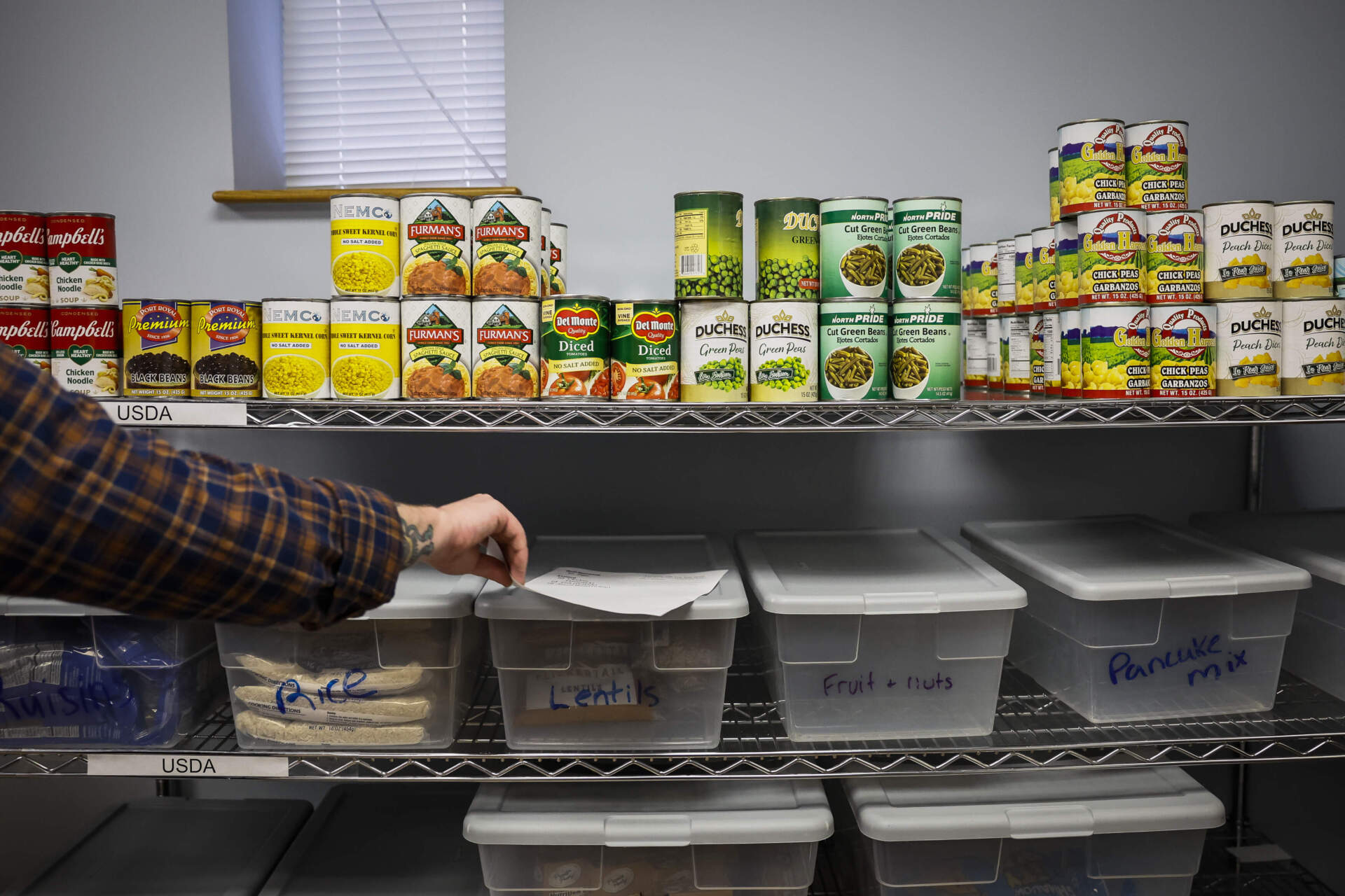 A client advocate at Action for Boston Community Development selects canned goods and pantry staples for client in need of food on Oct. 30. (Erin Clark/The Boston Globe via Getty Images)