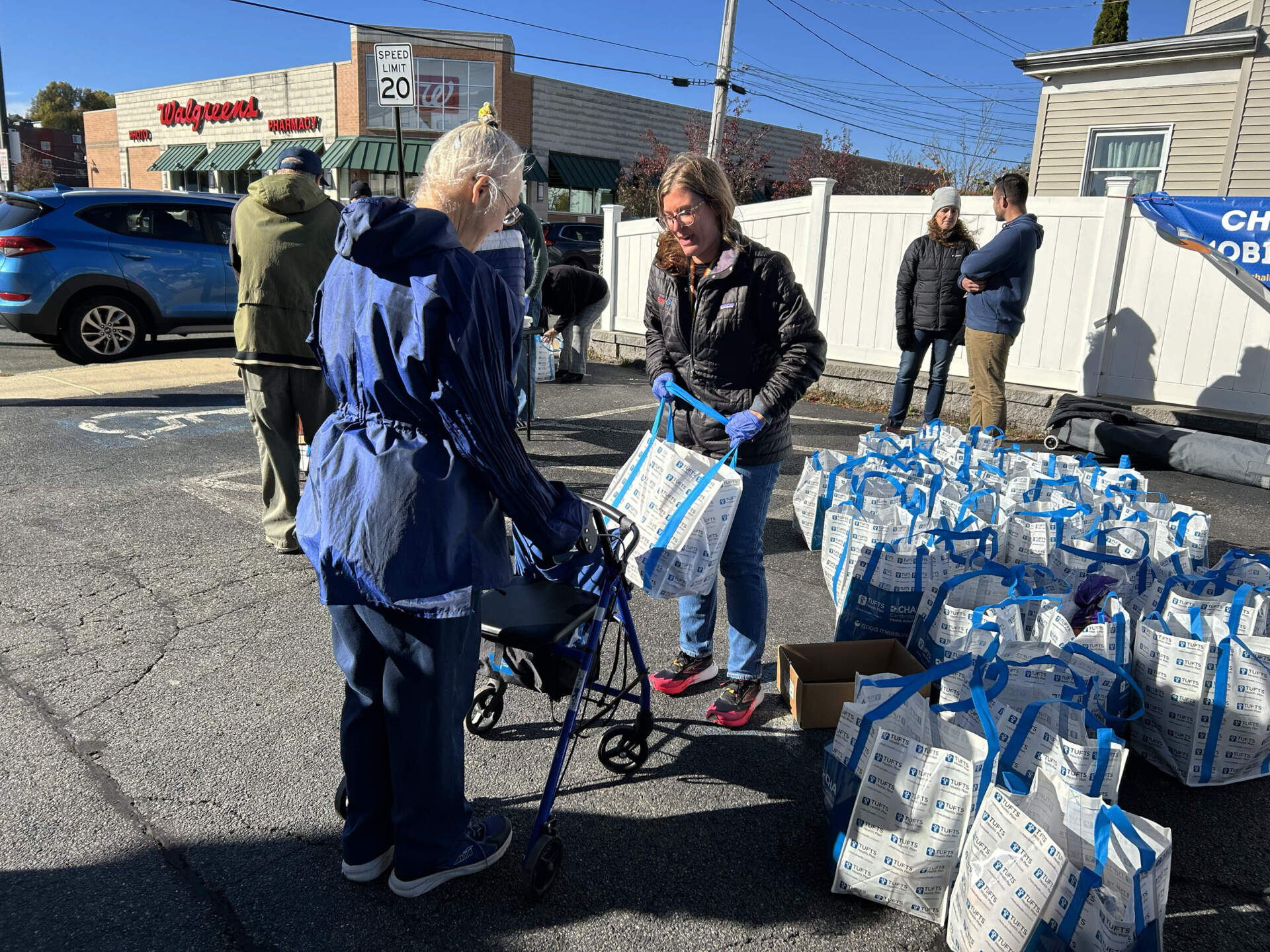 Lori Tivay says she would struggle to survive without the bag of groceries Stacy Fickler hands her at the Revere Care Center. (Martha Bebinger/WBUR)