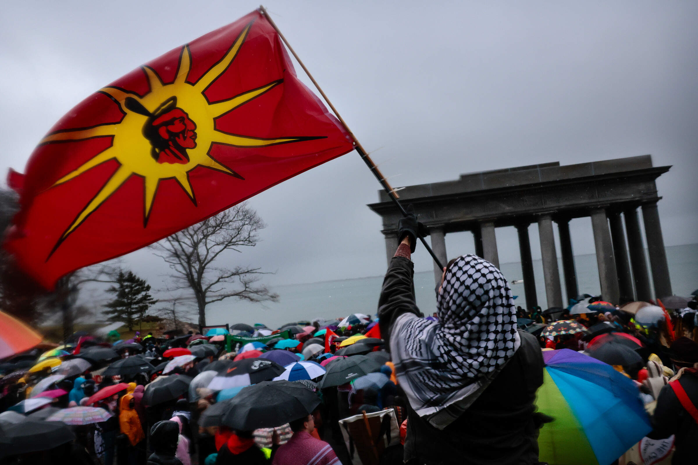 A demonstrator raises a flag as marchers gather at Plymouth Rock during the National Day of Mourning on Coles Hill in 2024. (Craig F. Walker/The Boston Globe via Getty Images)