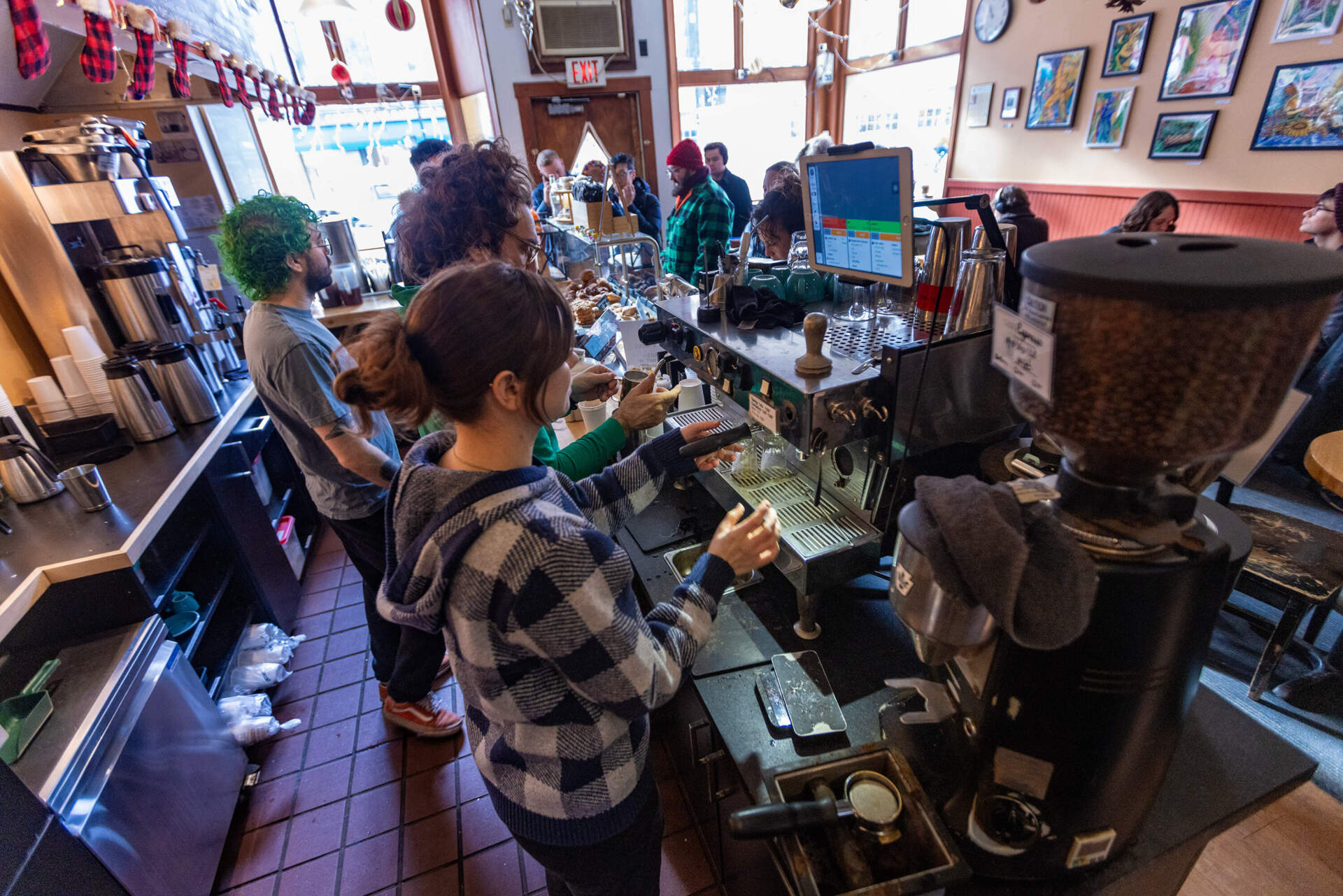 Baristas at the 1369 Coffeehouse in Inman Square prepare coffee drinks for a long line of customers in the morning. (Jesse Costa/WBUR)