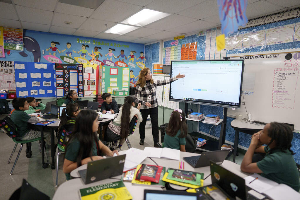 A teacher points to a board as students listen in a fourth grade classroom at William Jefferson Clinton Elementary in Compton, Calif., Thursday, Feb. 6, 2025. (AP Photo/Eric Thayer)