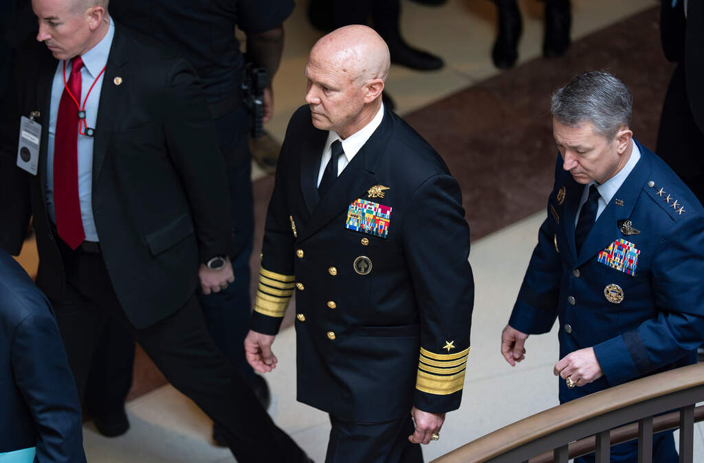 U.S. Navy Adm. Frank "Mitch" Bradley and Gen. Dan Caine, right, are escorted to a classified briefing for top congressional lawmakers overseeing national security as they investigate how Defense Secretary Pete Hegseth handled a military strike on a suspected drug smuggling boat near Venezuela. (J. Scott Applewhite/AP)