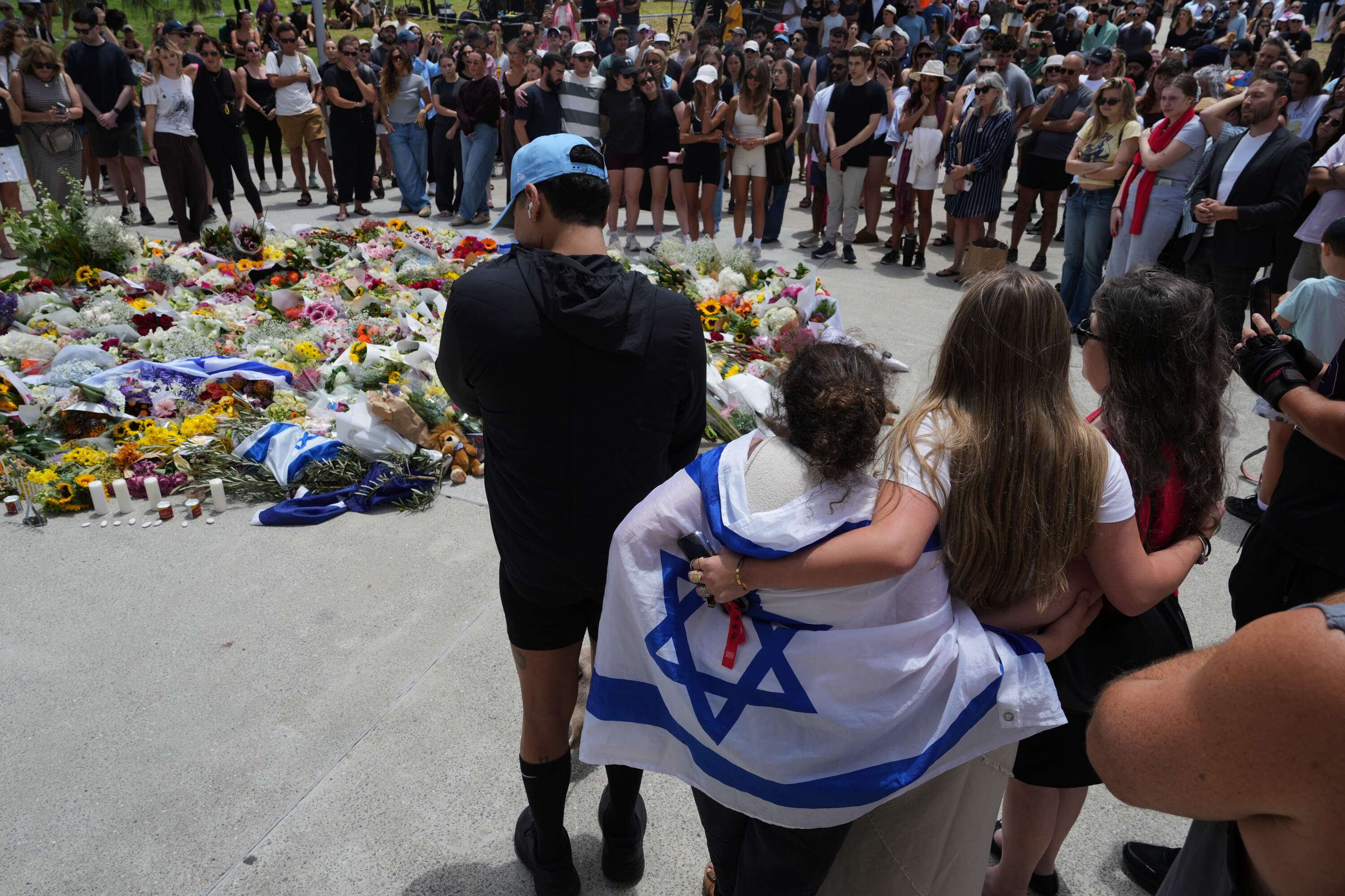 People gather around a growing flower tribute to shooting victims outside the Bondi Pavilion at Sydney's Bondi Beach, Monday, Dec. 15, 2025, a day after a shooting. (Mark Baker/AP)