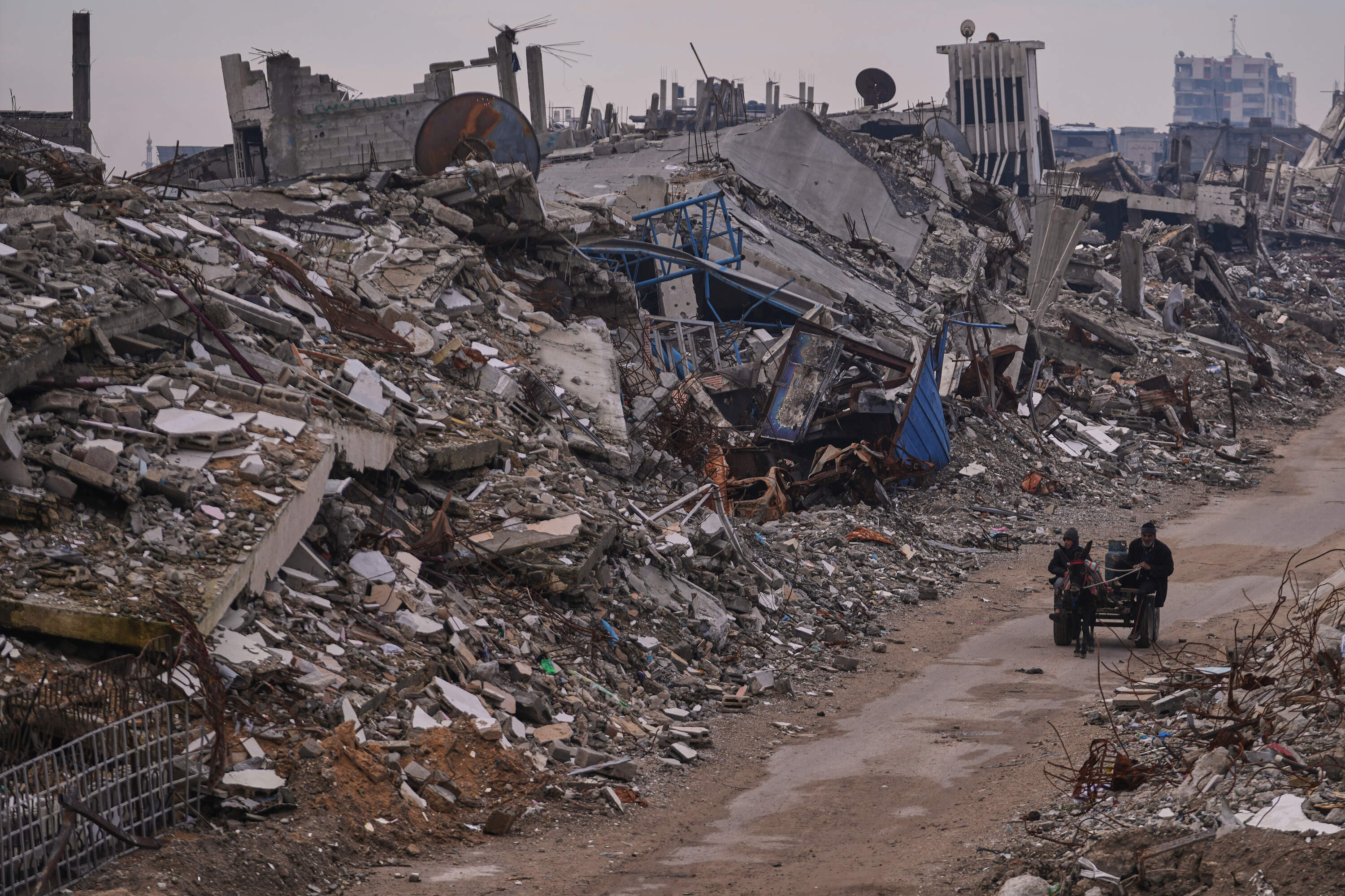 Palestinians pass along a street surrounded by buildings destroyed during Israeli air and ground operations in the Sheikh Radwan neighborhood, in Gaza City, Tuesday, Dec. 30, 2025. (Abdel Kareem Hana/AP)