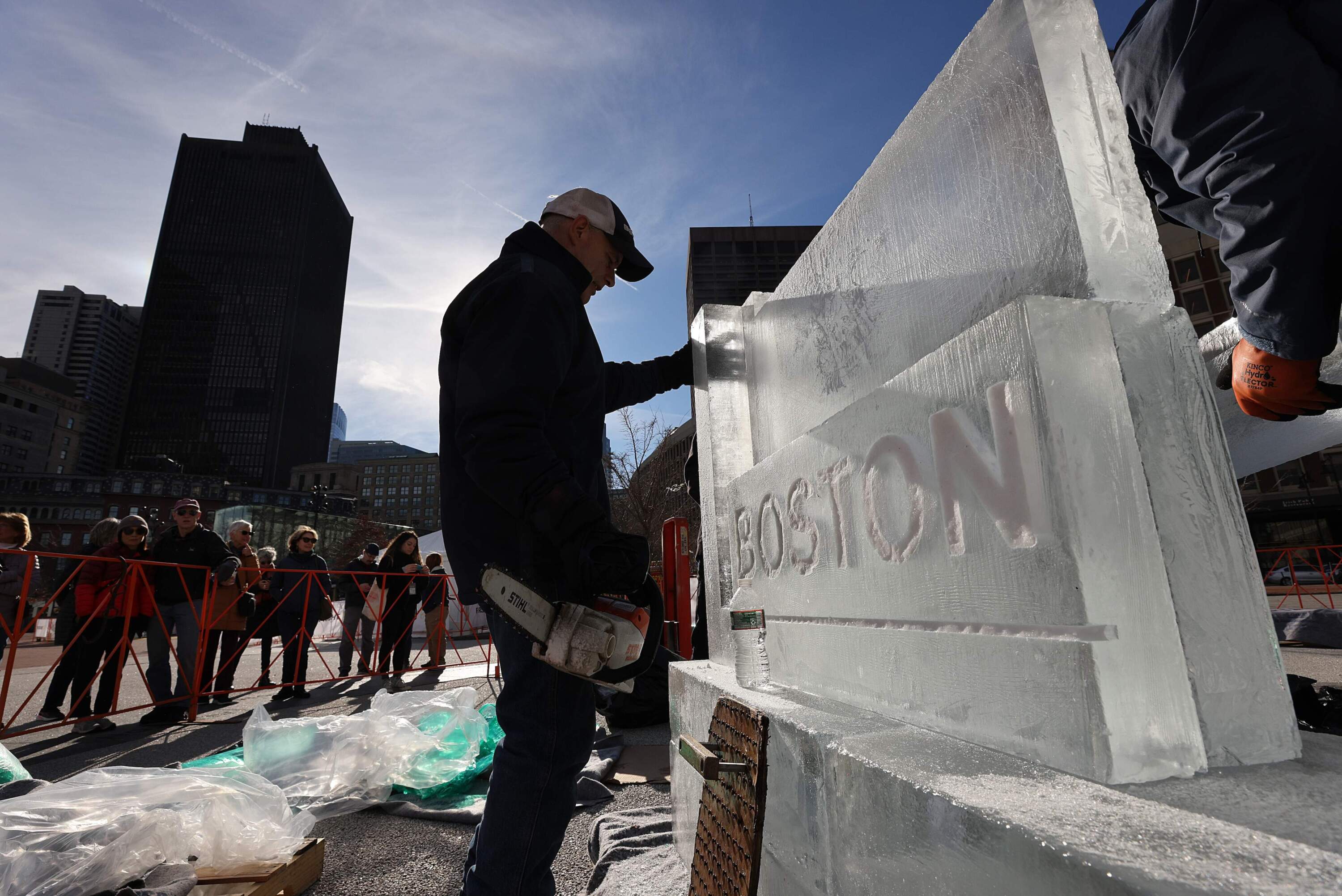 Steven Rose of Boston Ice Effects, left, steadies the ice sculpture on Dec. 31, 2024. The ice sculptures were assembled on City Hall Plaza for First Night celebrations. (Suzanne Kreiter/The Boston Globe via Getty Images)