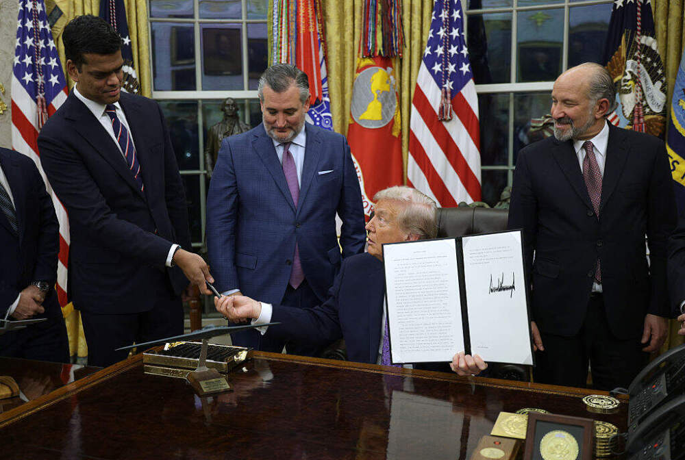 President Trump hands a pen to Senior White House Policy Advisor on AI Sriram Krishnan after signing an executive order that curbs states' ability to regulate AI on December 11, 2025. (Alex Wong/Getty Images)