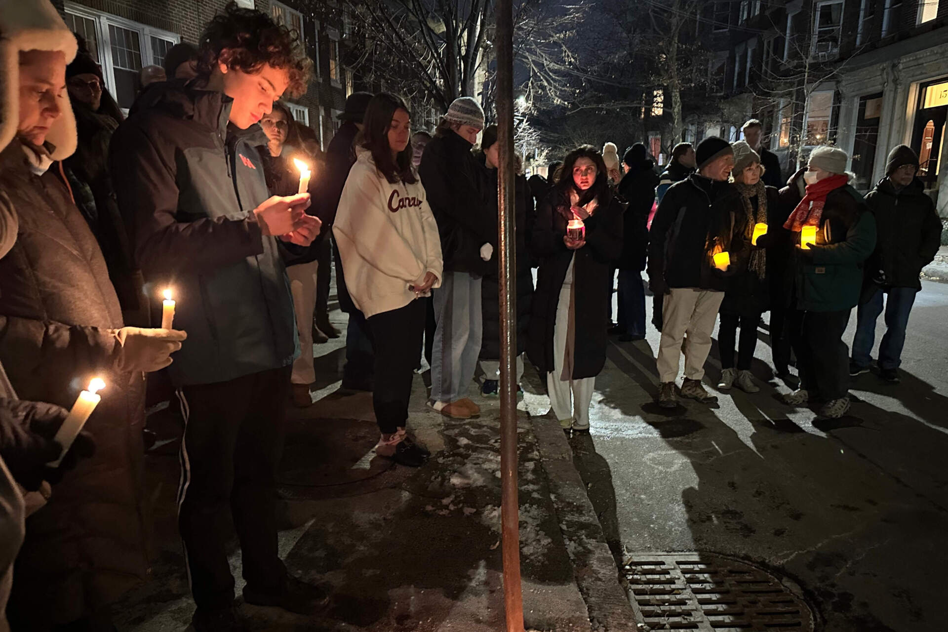 A crowd of people holding candles gather outside the home of MIT professor Nuno F.G. Loureiro in Brookline, Mass., on Dec. 16. (Leah Willingham/AP)