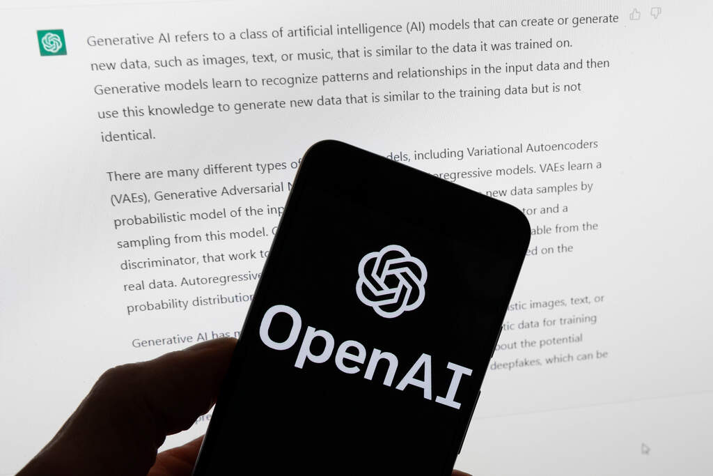 The OpenAI logo is displayed on a mobile phone in front of a computer screen with output from ChatGPT, March 21, 2023, in Boston. (Michael Dwyer/AP File)