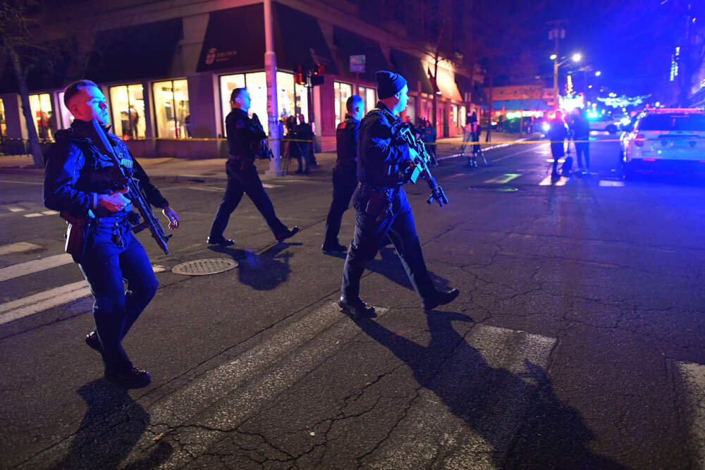 Law enforcement officials carry rifles in a neighborhood near Brown University on Saturday during the investigation of the campus shooting. (Steven Senne/AP)