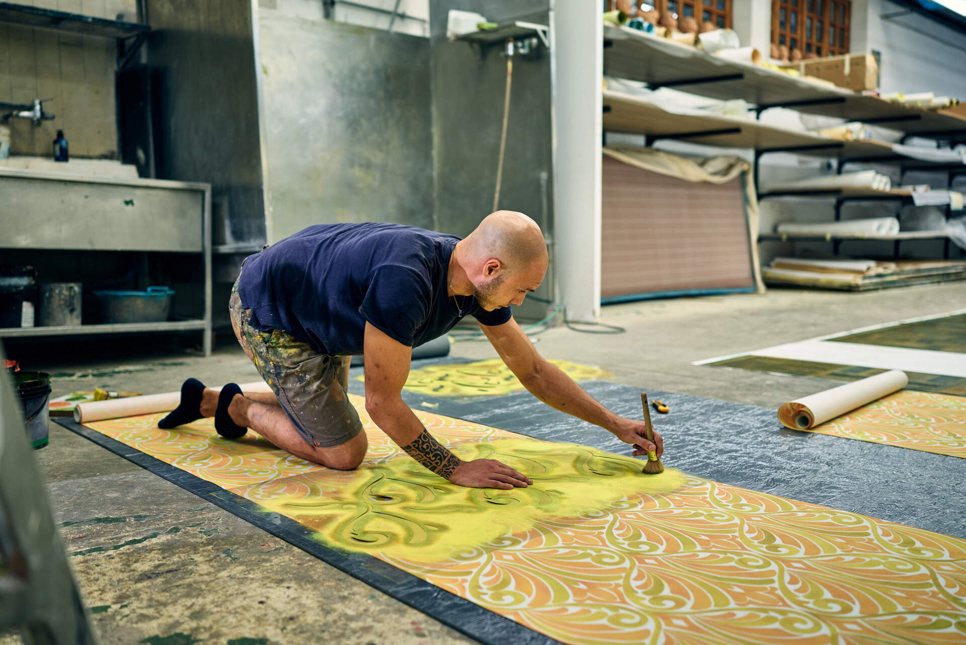 A man hand-paints wallpaper in the decoration workshop at San Patrignano. (Wilson Santinelli for WBUR)