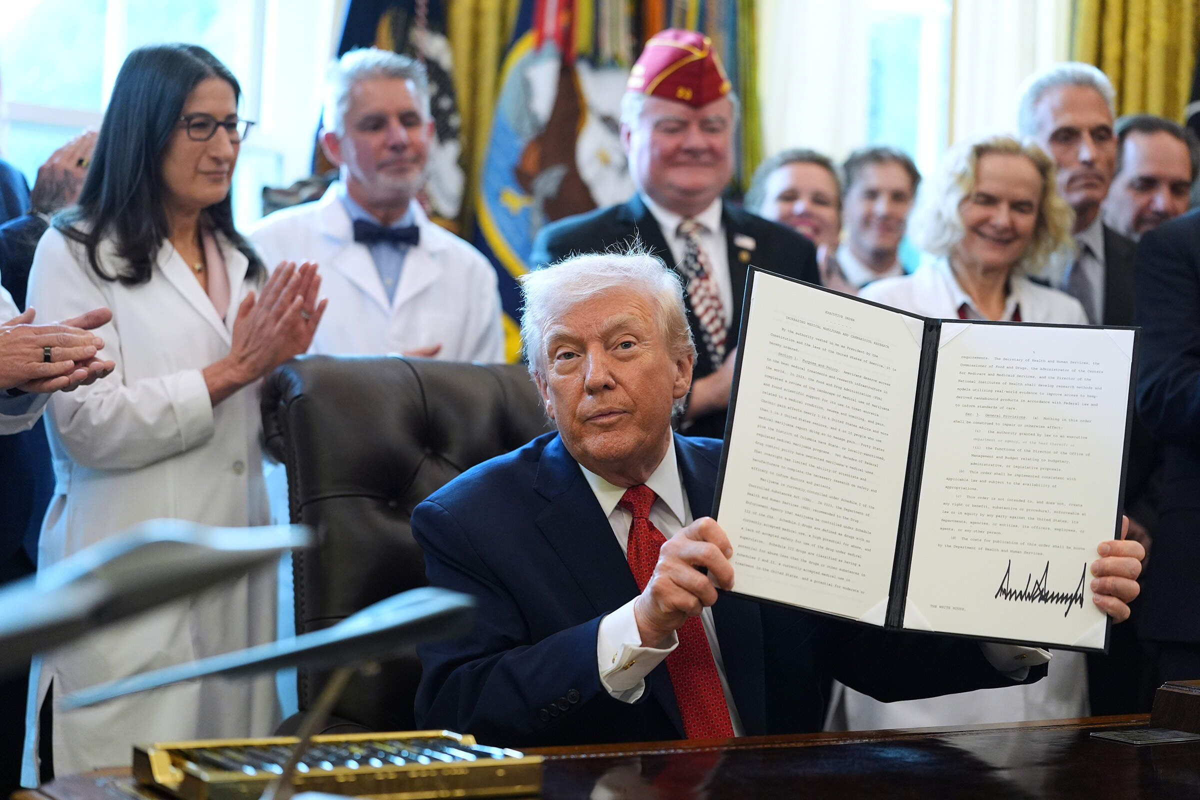 President Trump displays an executive order reclassifying marijuana as a less dangerous drug in the Oval Office on Dec. 18, 2025. (Evan Vucci/AP)