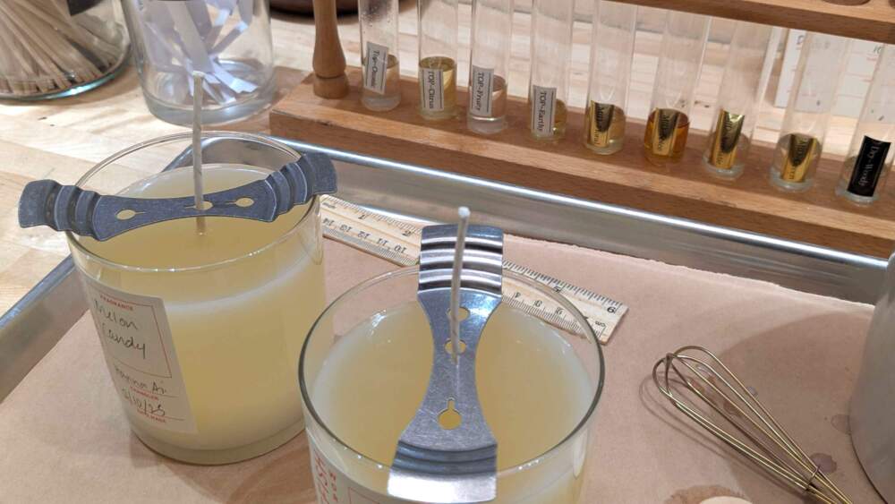 When a candle is first poured, the wick needs to be stabilized in the center of the wax so the candle can burn evenly when it's cooled. (Hanna Ali/WBUR)