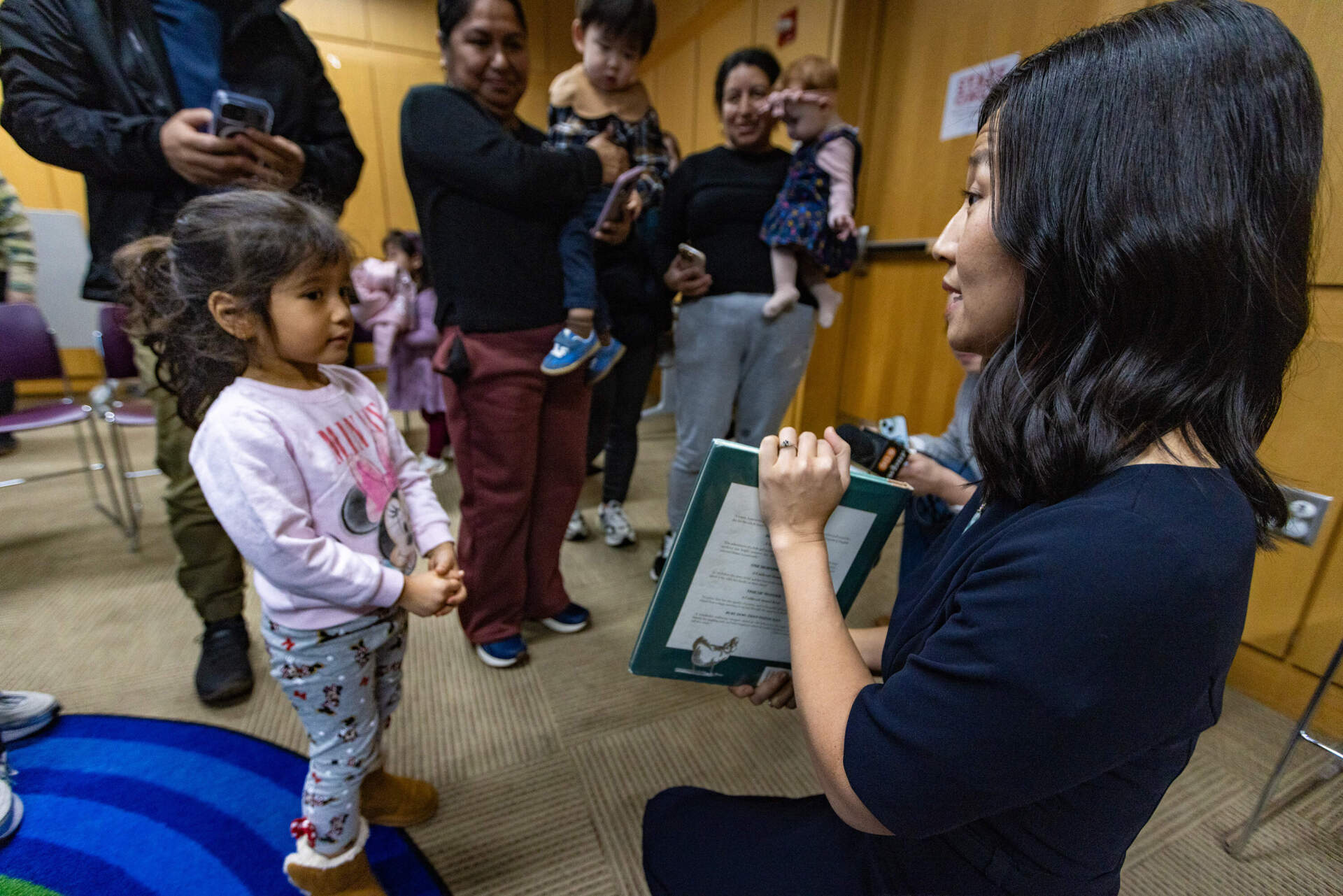 Michelle Wu gives a copy of “Make Way for Ducklings” to 3-year old Intisar  Hanyf at the Boston Public Library's Brighton branch. (Jesse Costa/WBUR)