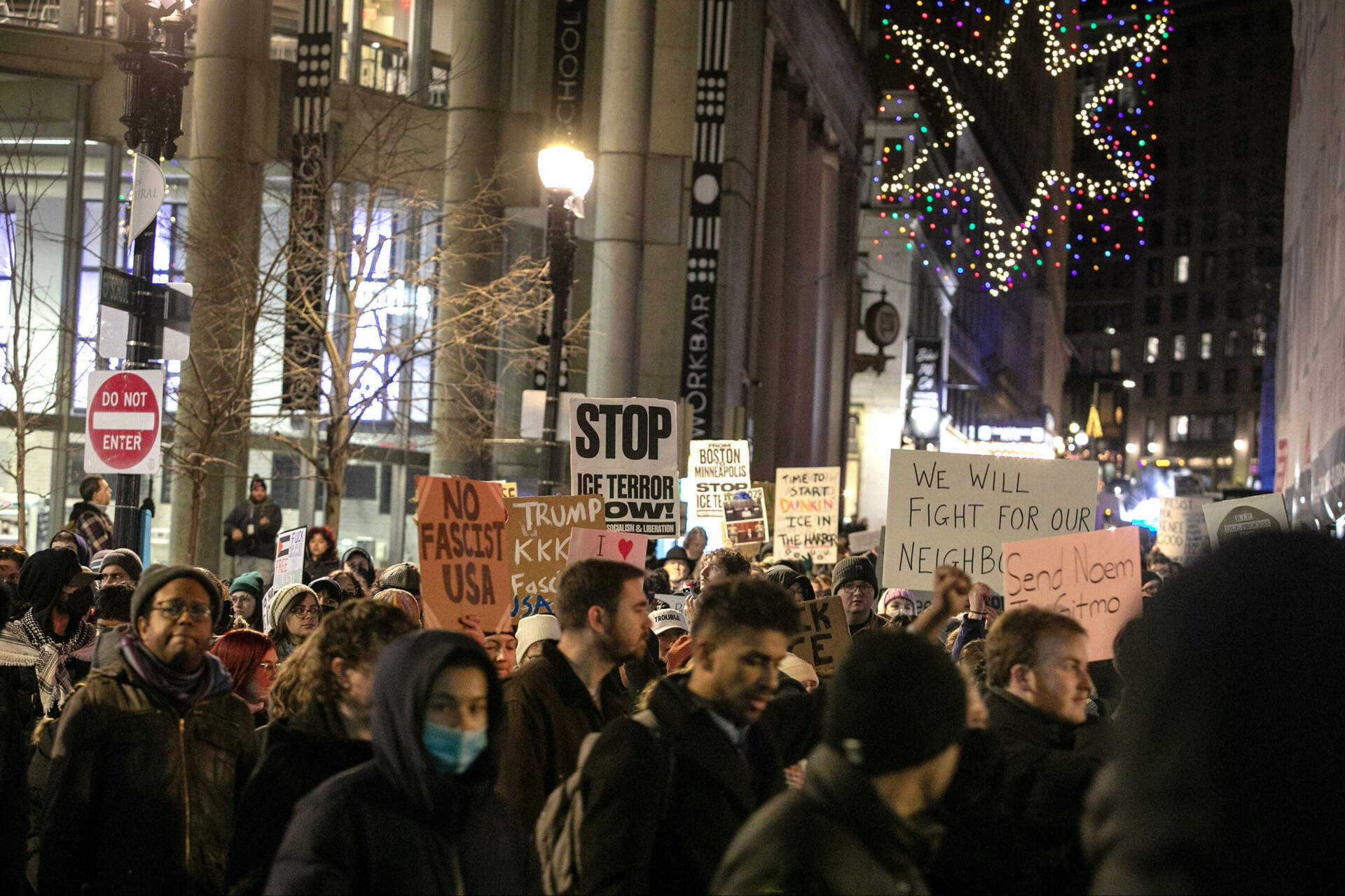 Protesters hoist signs as they march through downtown Boston. (Robin Lubbock/WBUR)