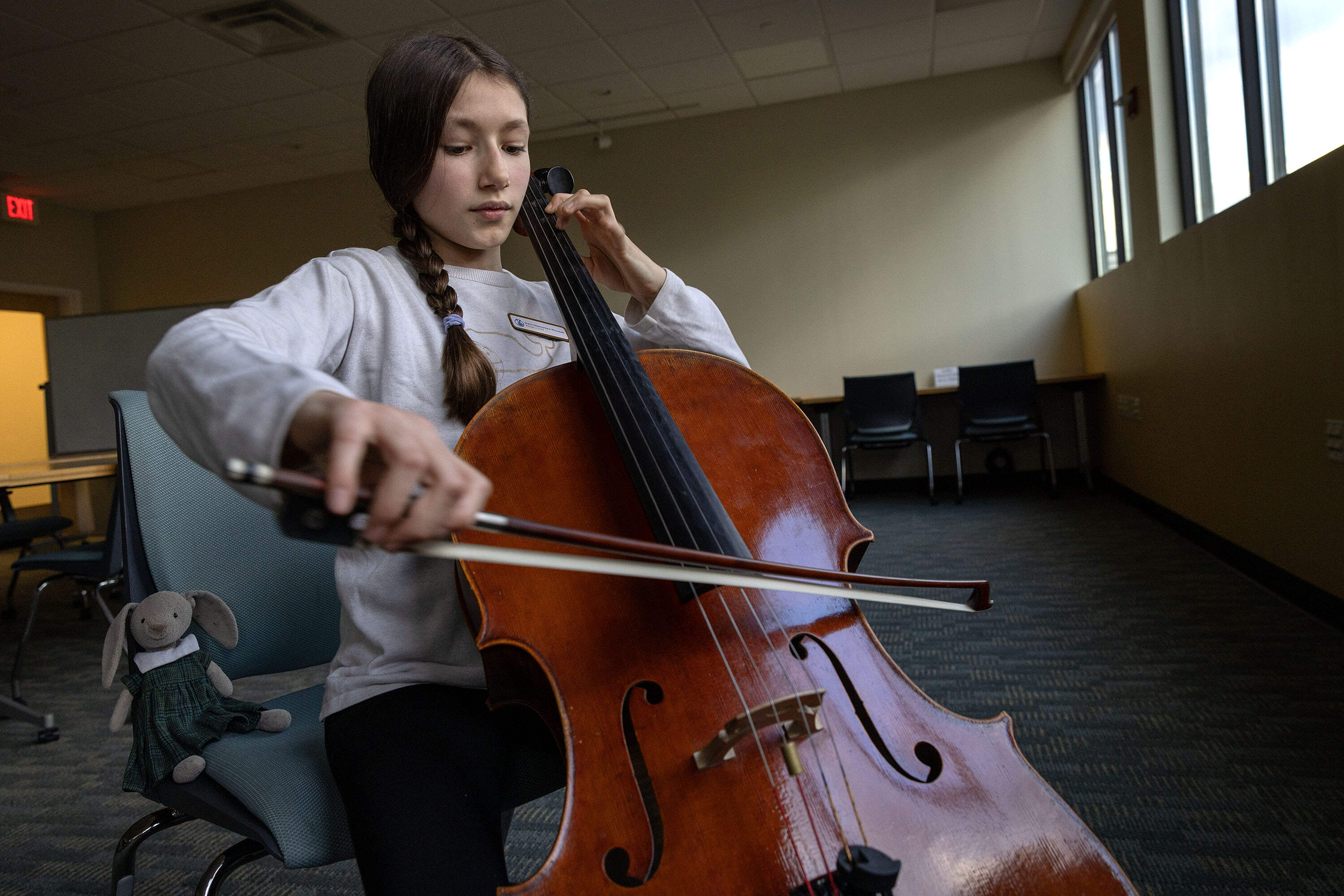 Sofia Hernandez-Williams plays cello at WBUR with her stuffy Caitriona by her side. (Robin Lubbock/WBUR)
